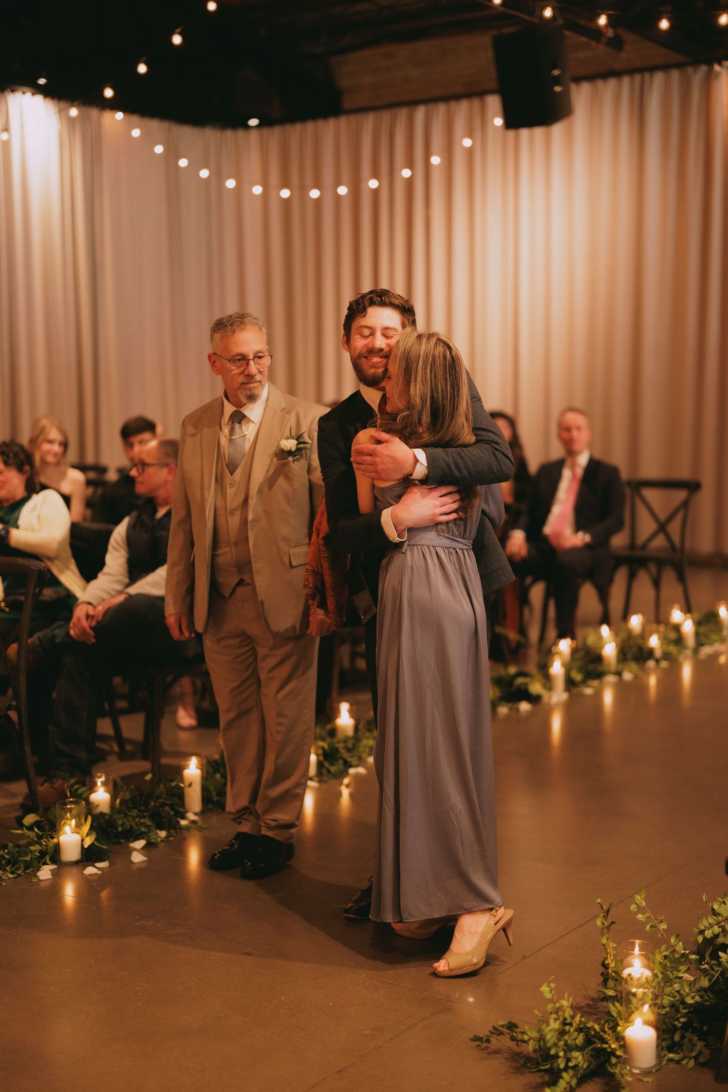 Wedding reception venue decorated with string lights, candles and elegant drapery.