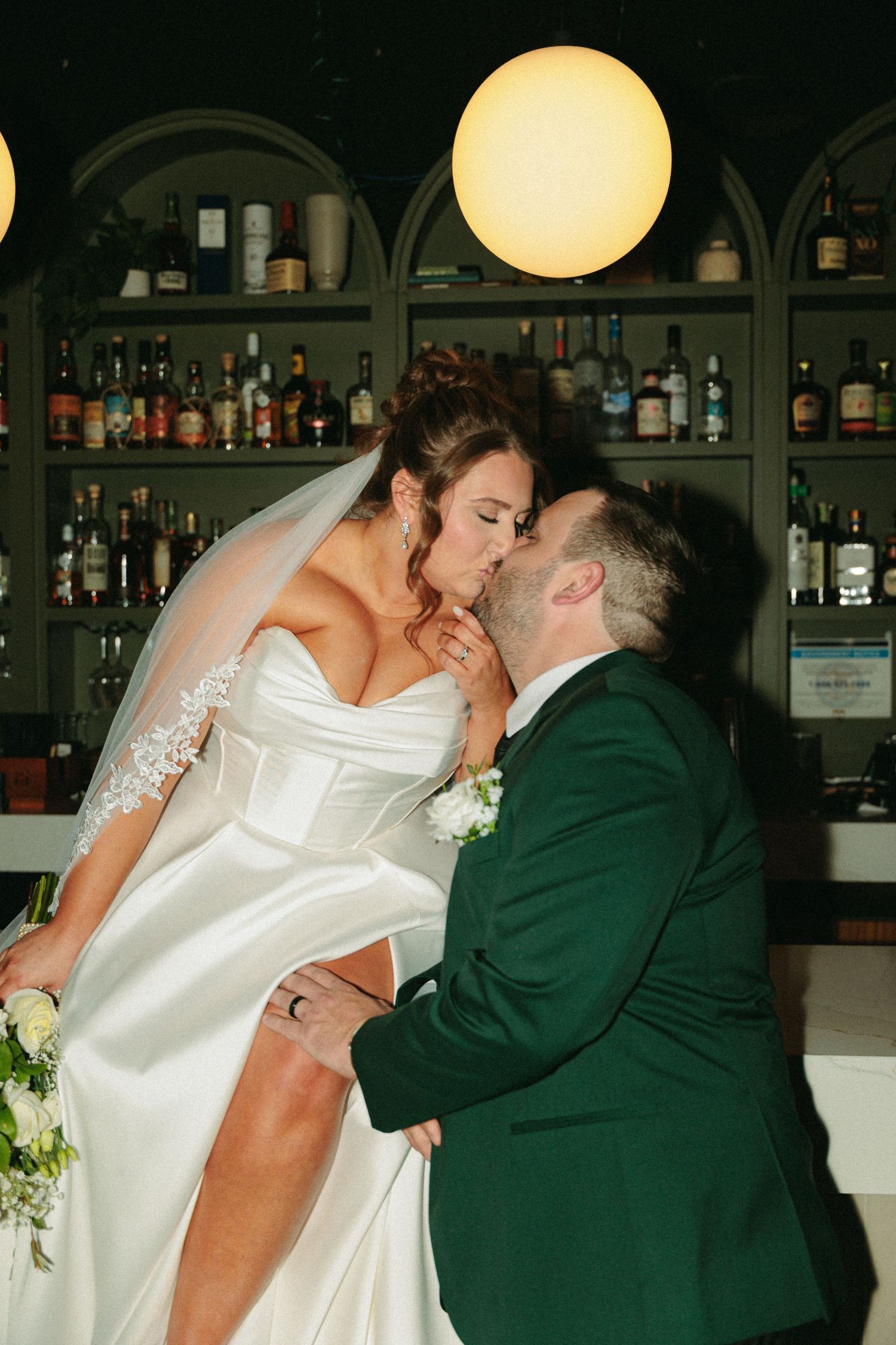 Romantic dance scene at a wedding reception with yellow lighting and bar backdrop.