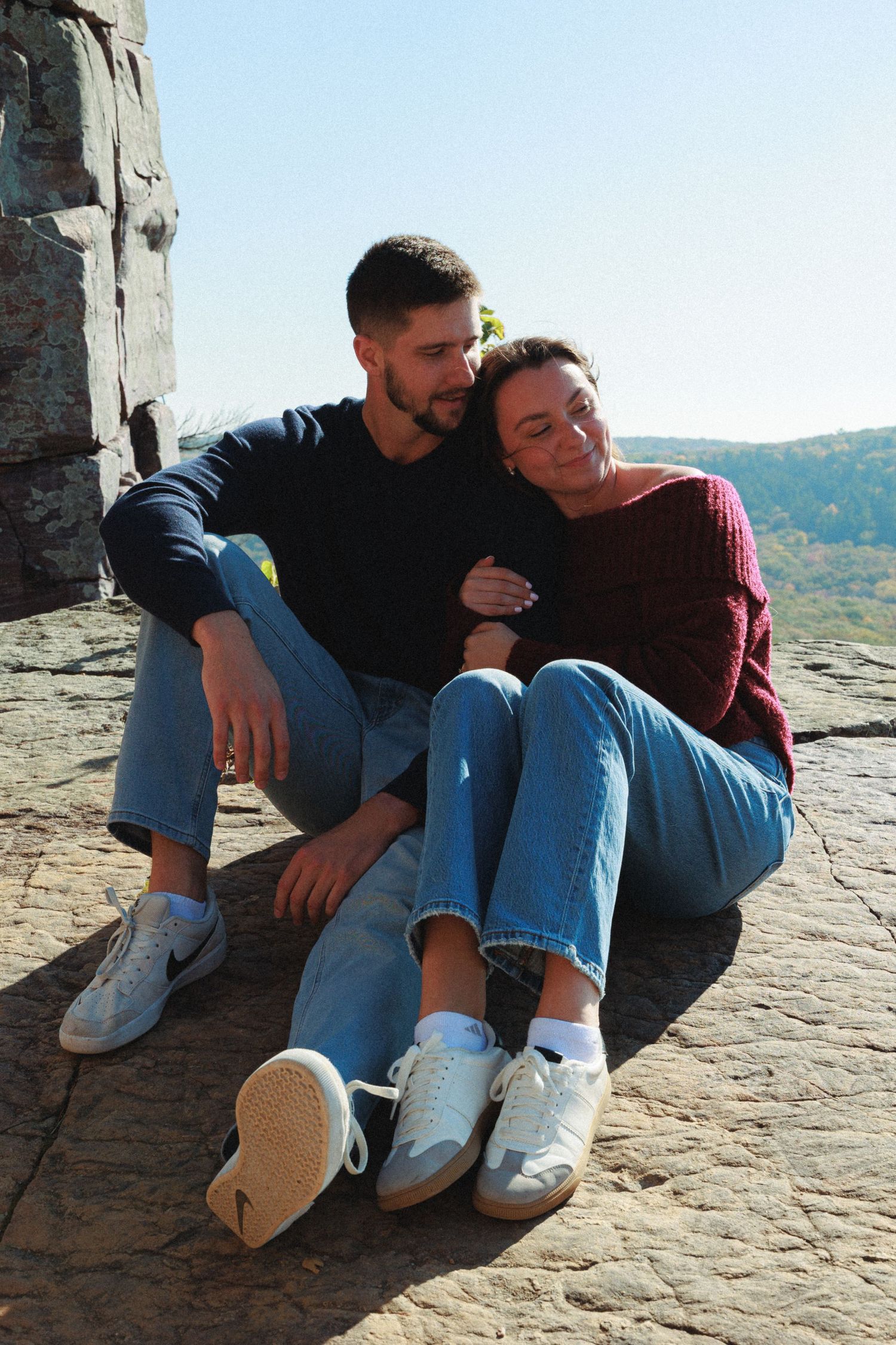 Couple relaxing together on rocky cliff overlook.