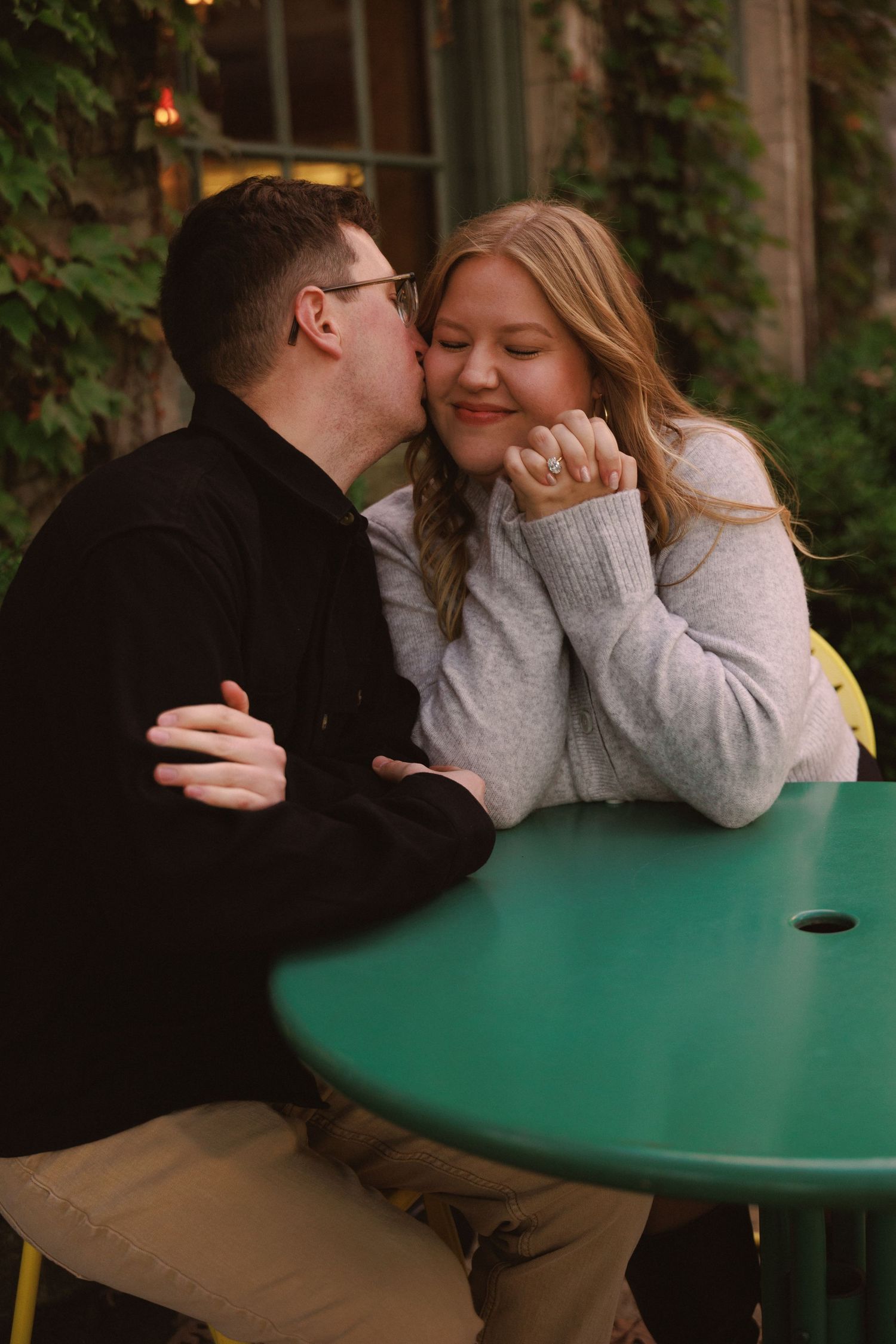 Couple sitting at green table sharing playful moment together.