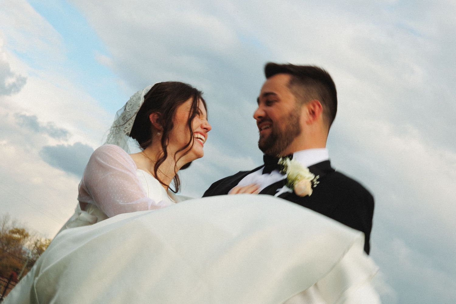 Romantic outdoor wedding portraits with flowing veil against autumn sky.