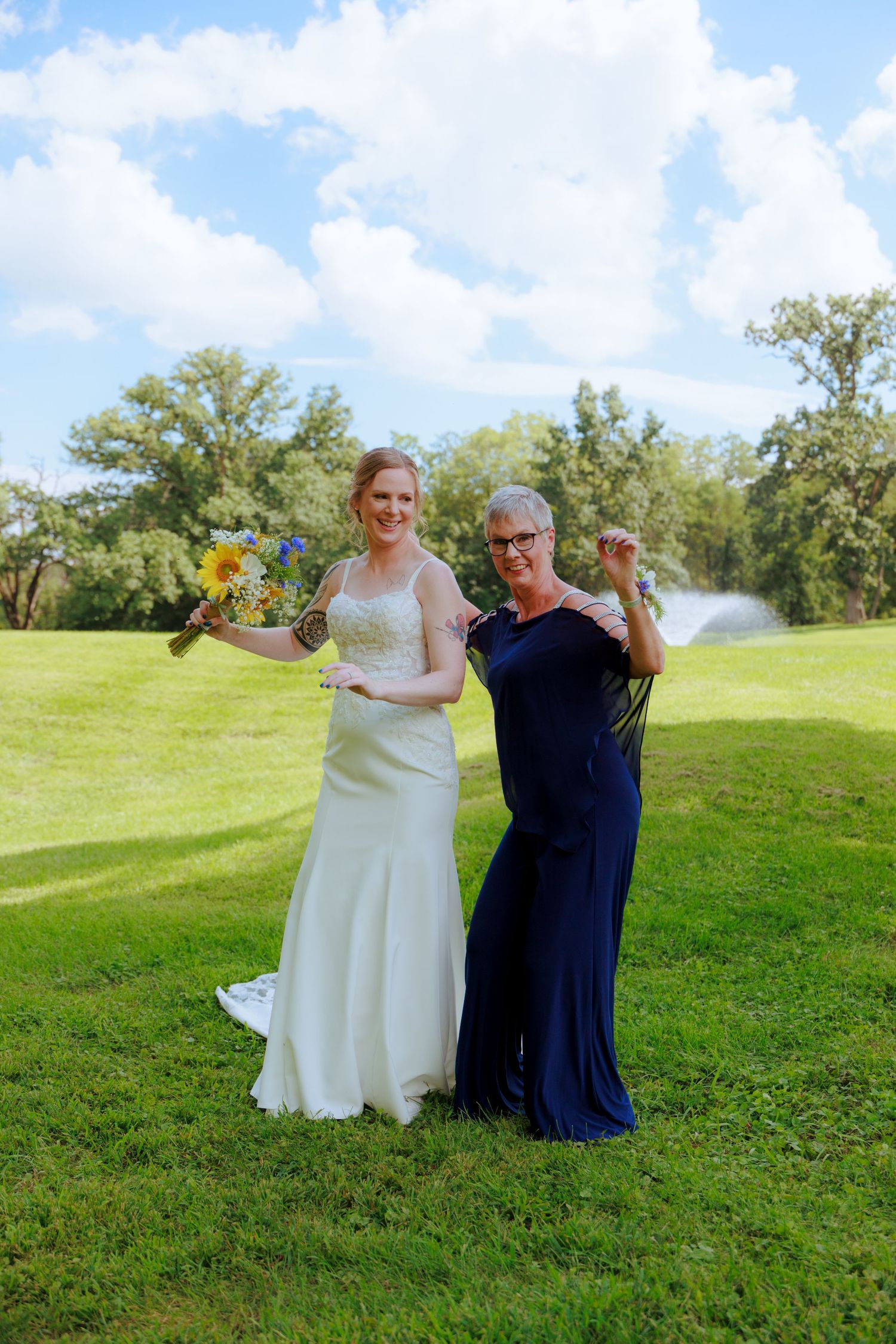Two people dancing and celebrating on a sunny green lawn.