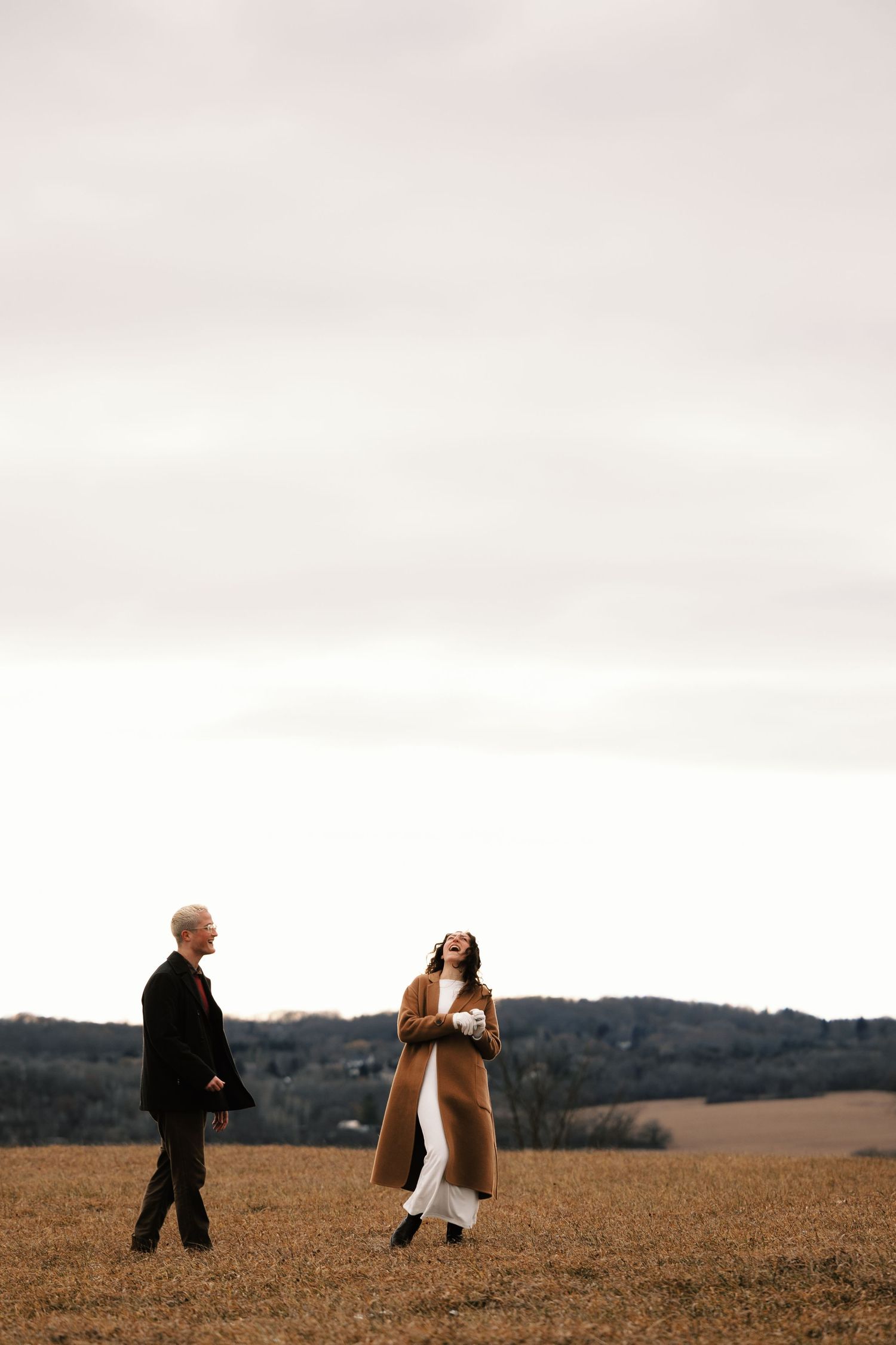 Couple walking together across a vast open field during golden hour.
