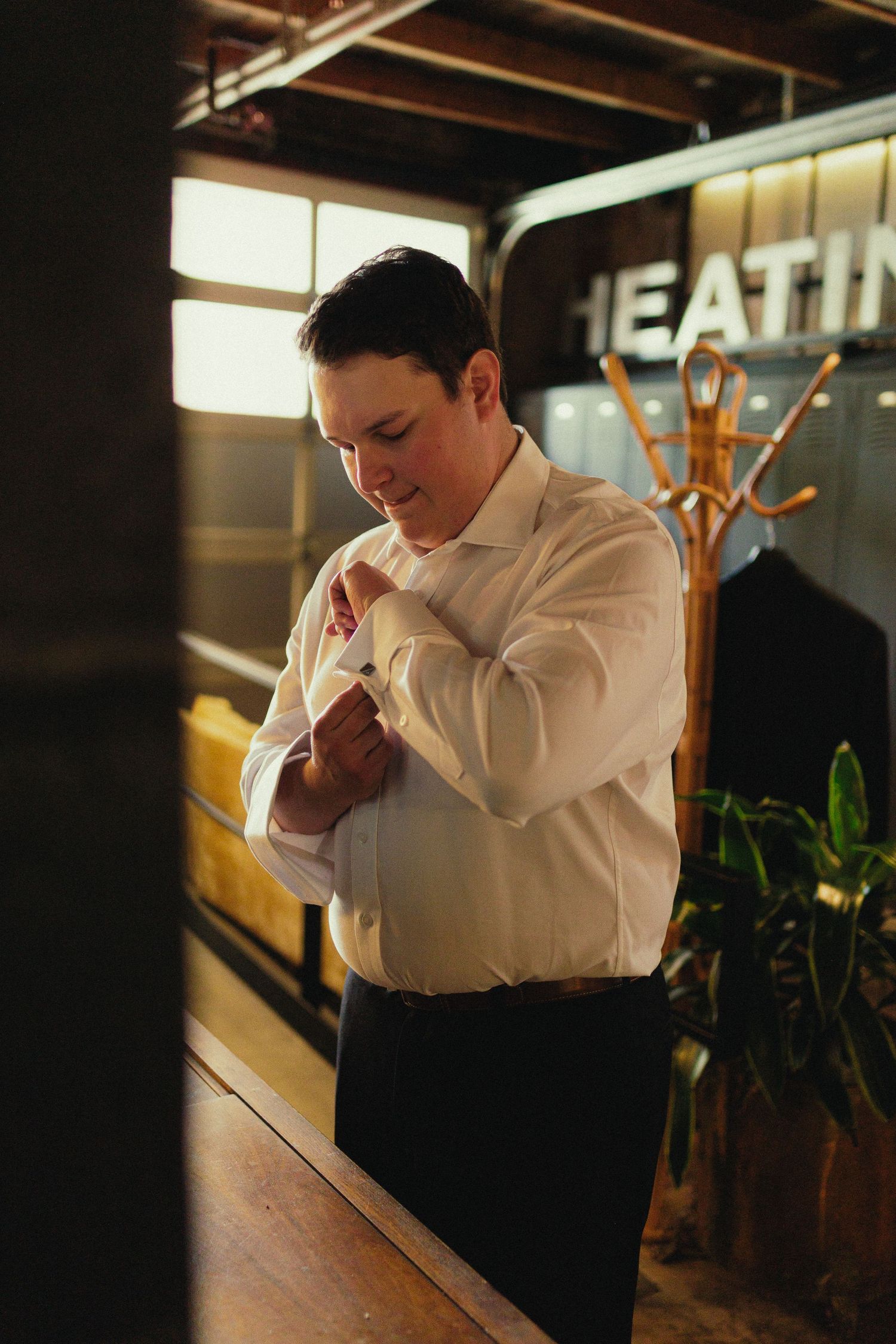 Person in white shirt adjusting their tie in low light setting.