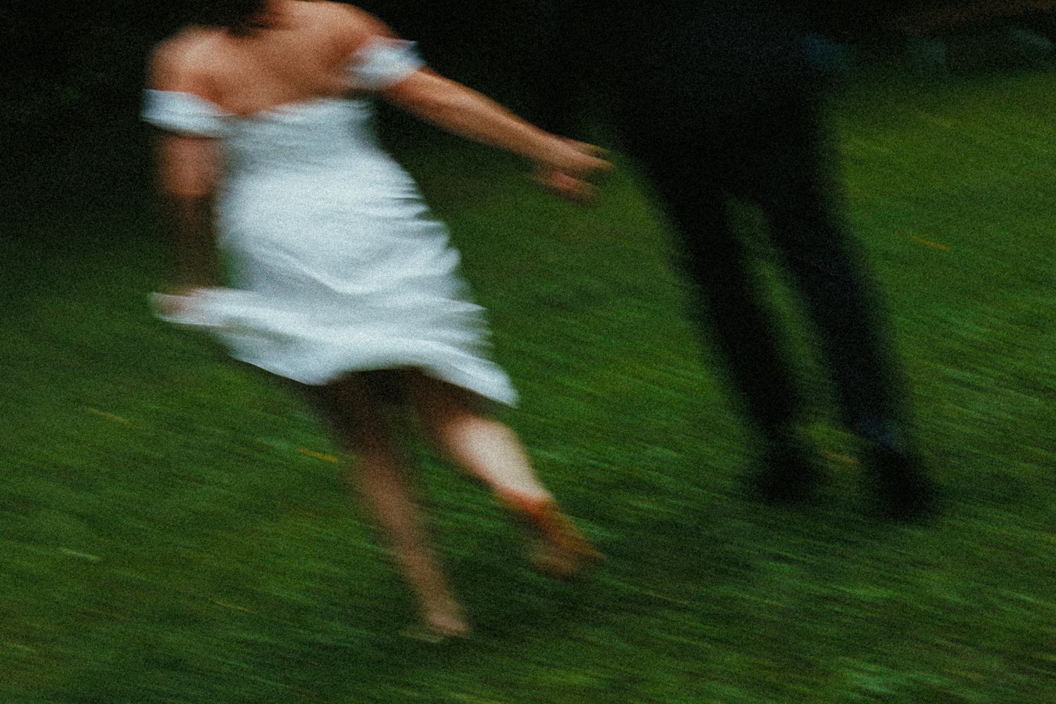 Blurred motion shot of people dancing on grass during an outdoor celebration.