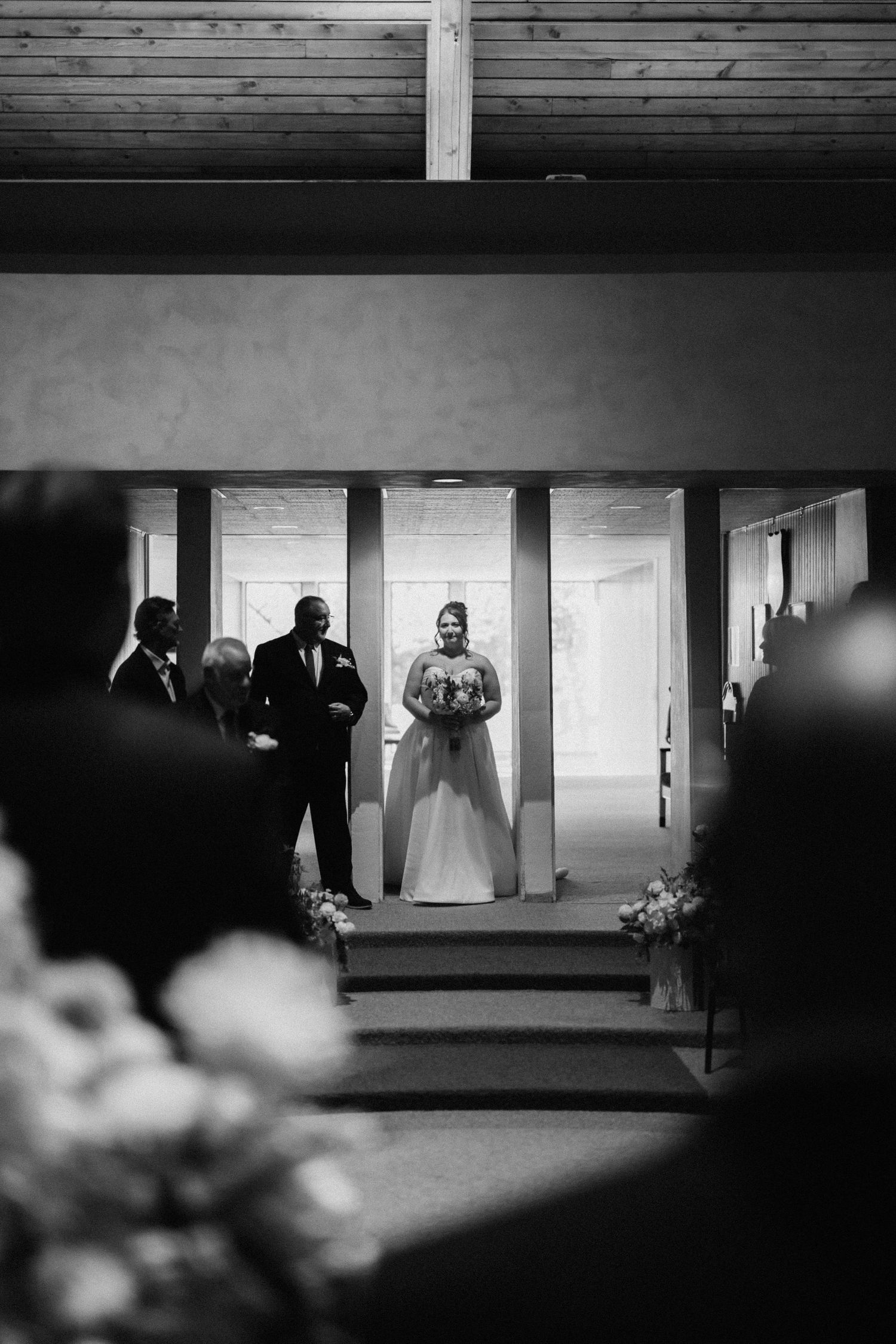 Black and white wedding ceremony scene with silhouettes of attendees in a hall.