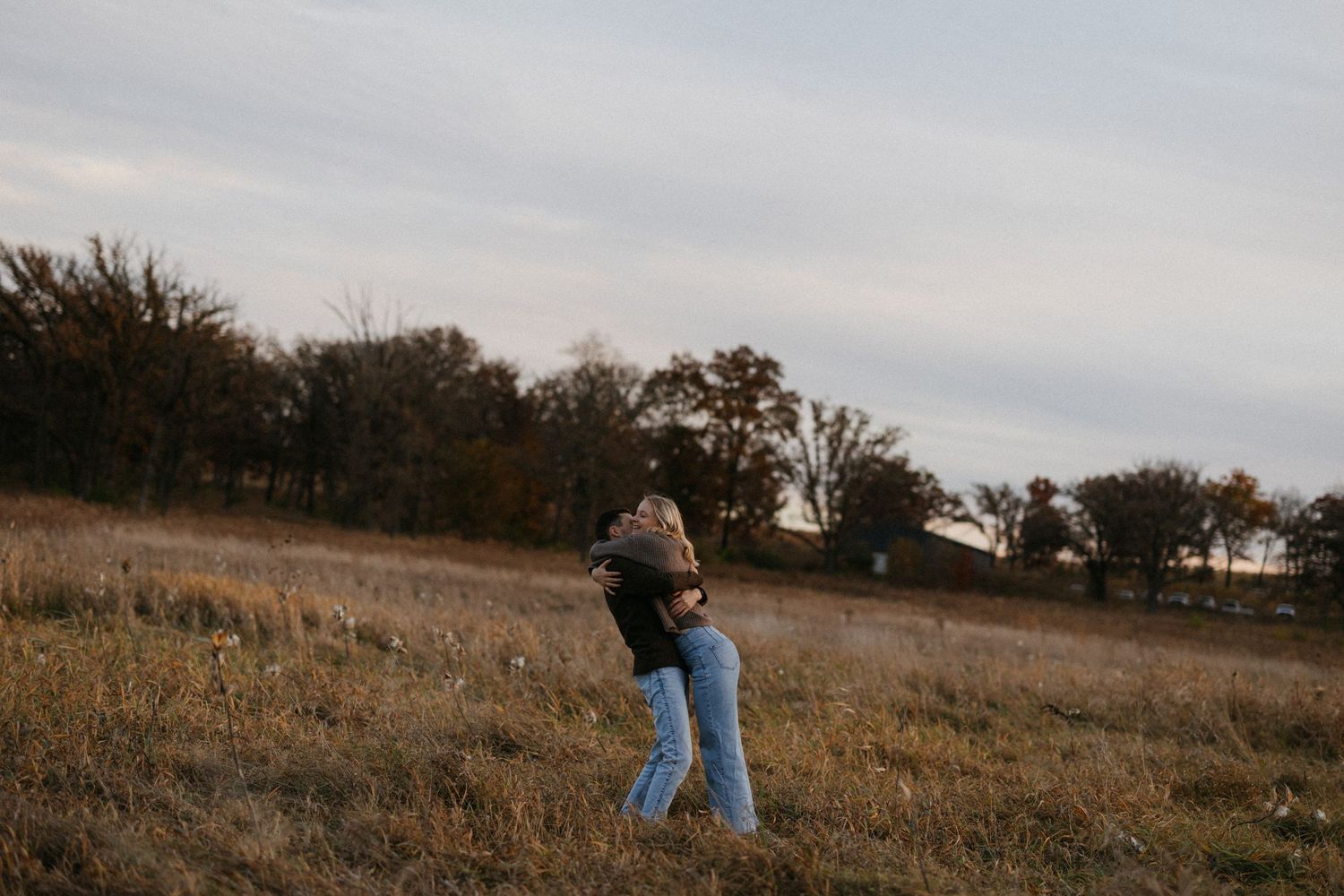 Distant view of couple walking together in an autumn field at dusk.