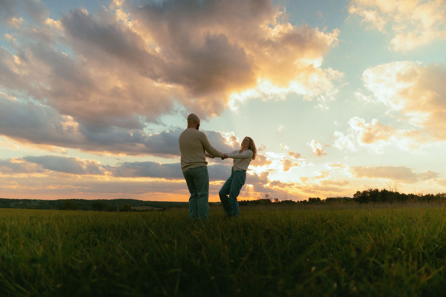 Silhouetted figures standing together in a field against a vibrant sunset sky.
