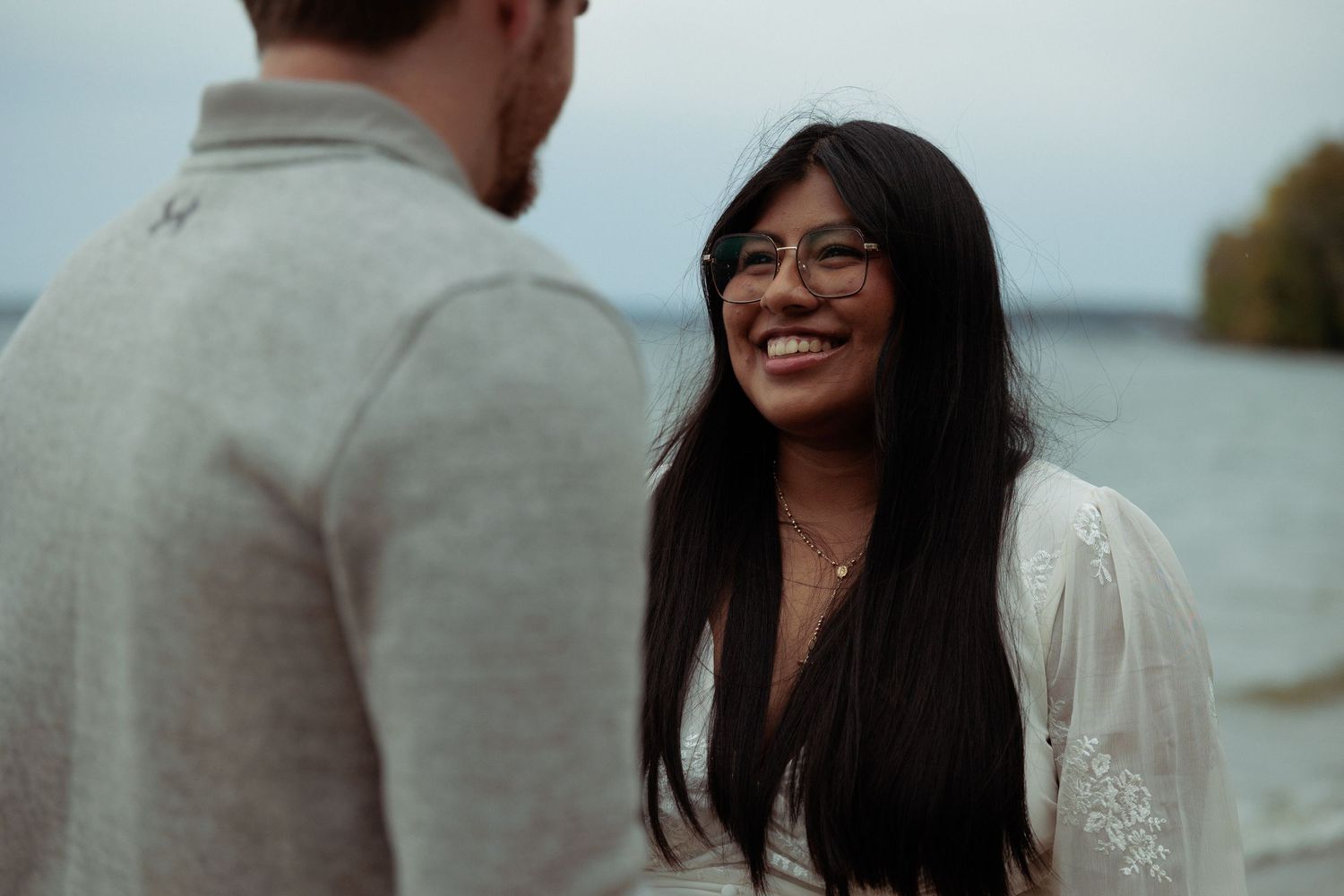 Candid moments between a couple on a cloudy beach.