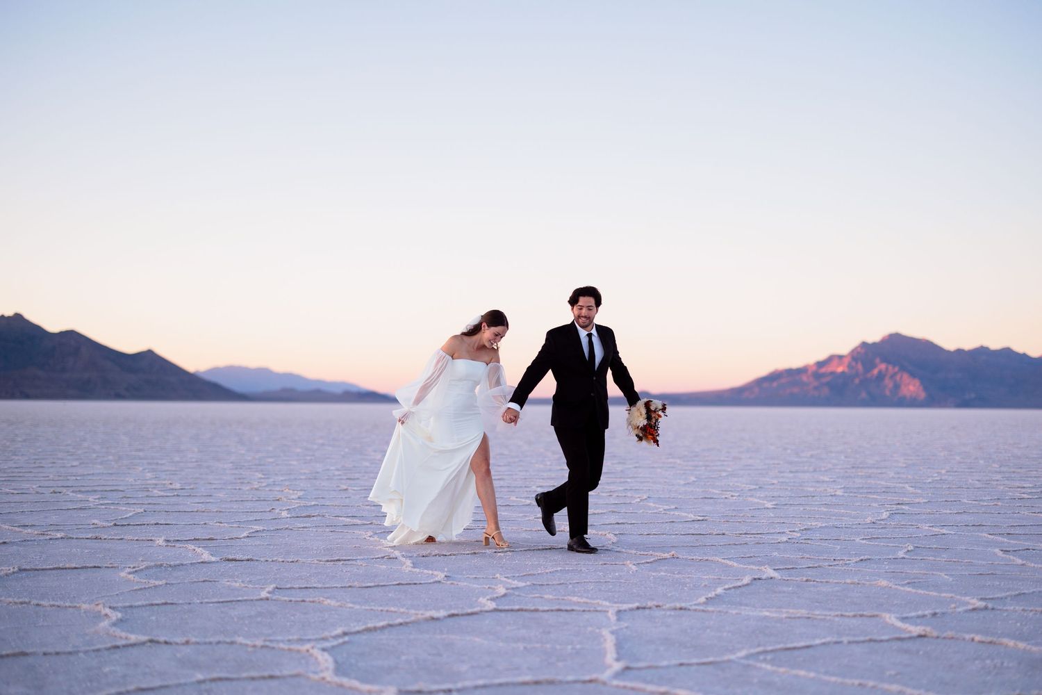 Panoramic view of wedding couple on vast utah salt flats with purple mountain range.