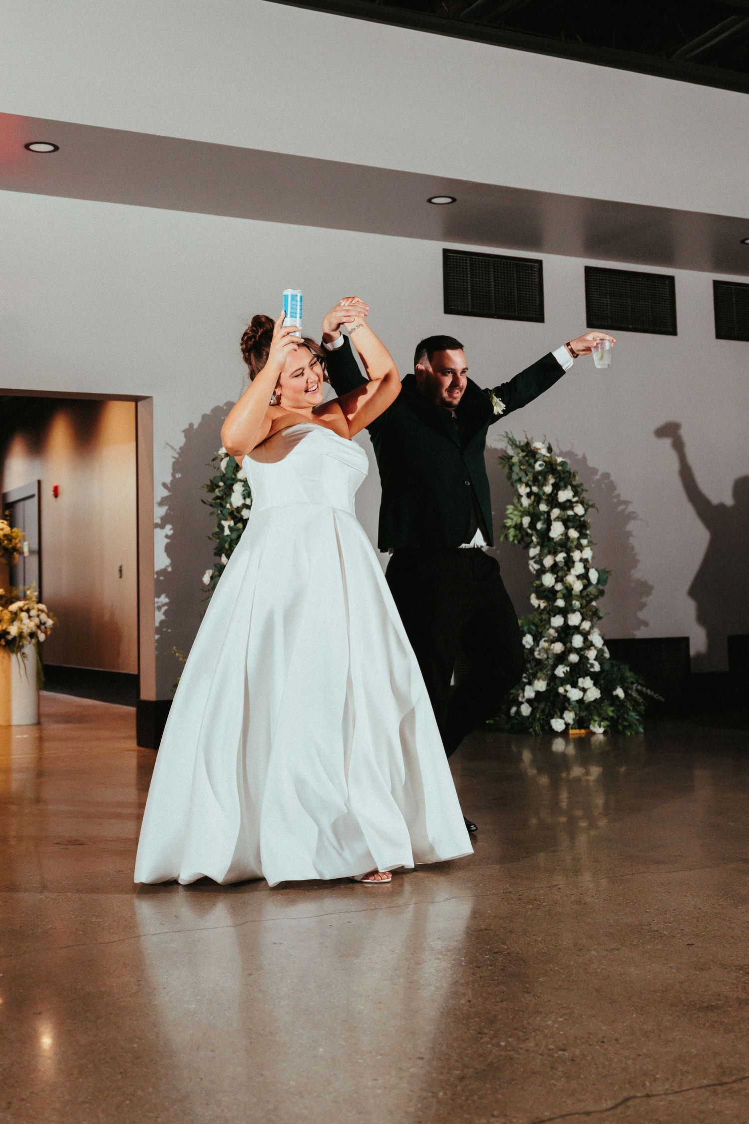 Wedding party dancing and celebrating on a polished floor with white gowns and formal attire.