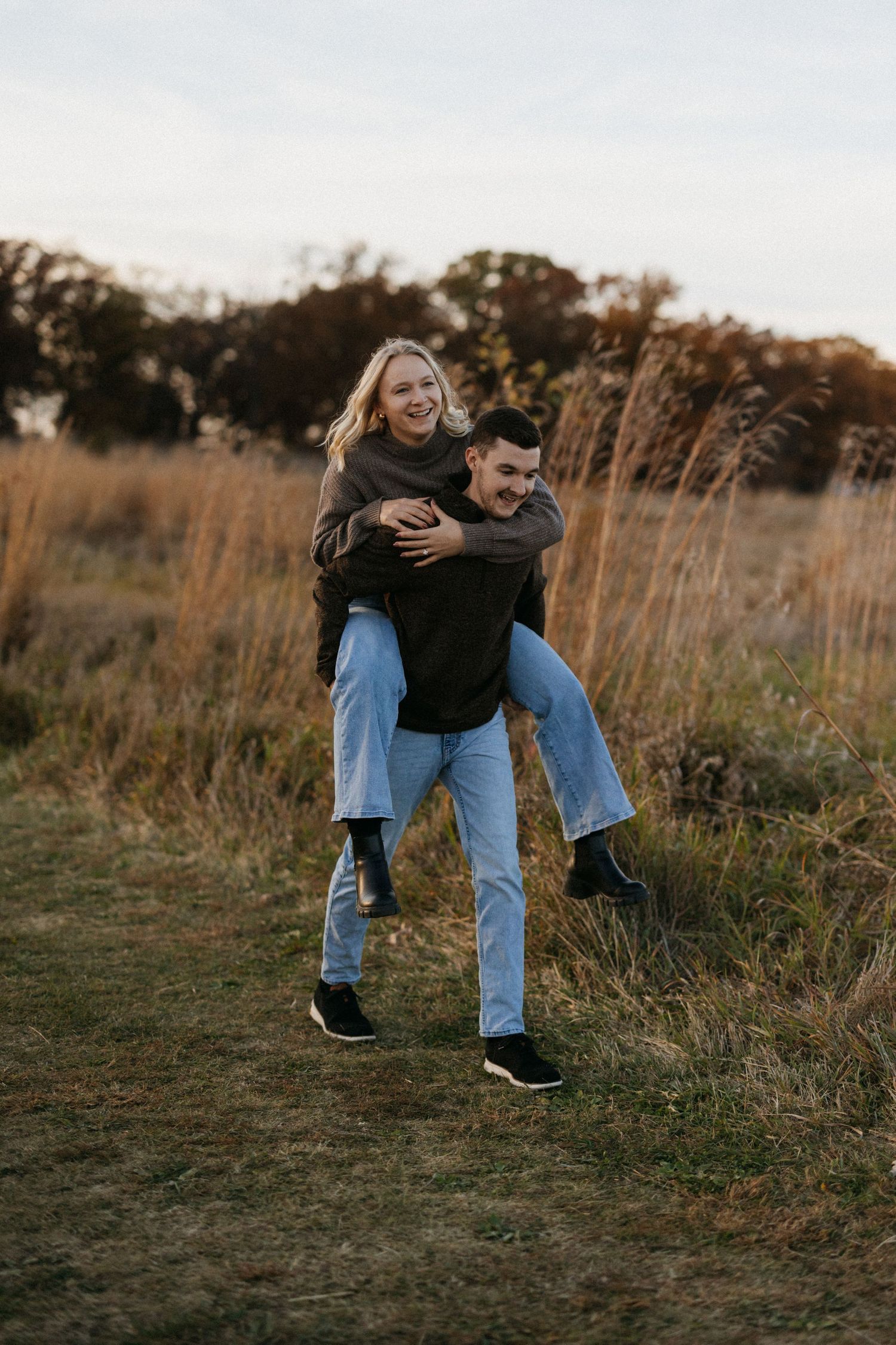 Playful couple having fun in a field during sunset.