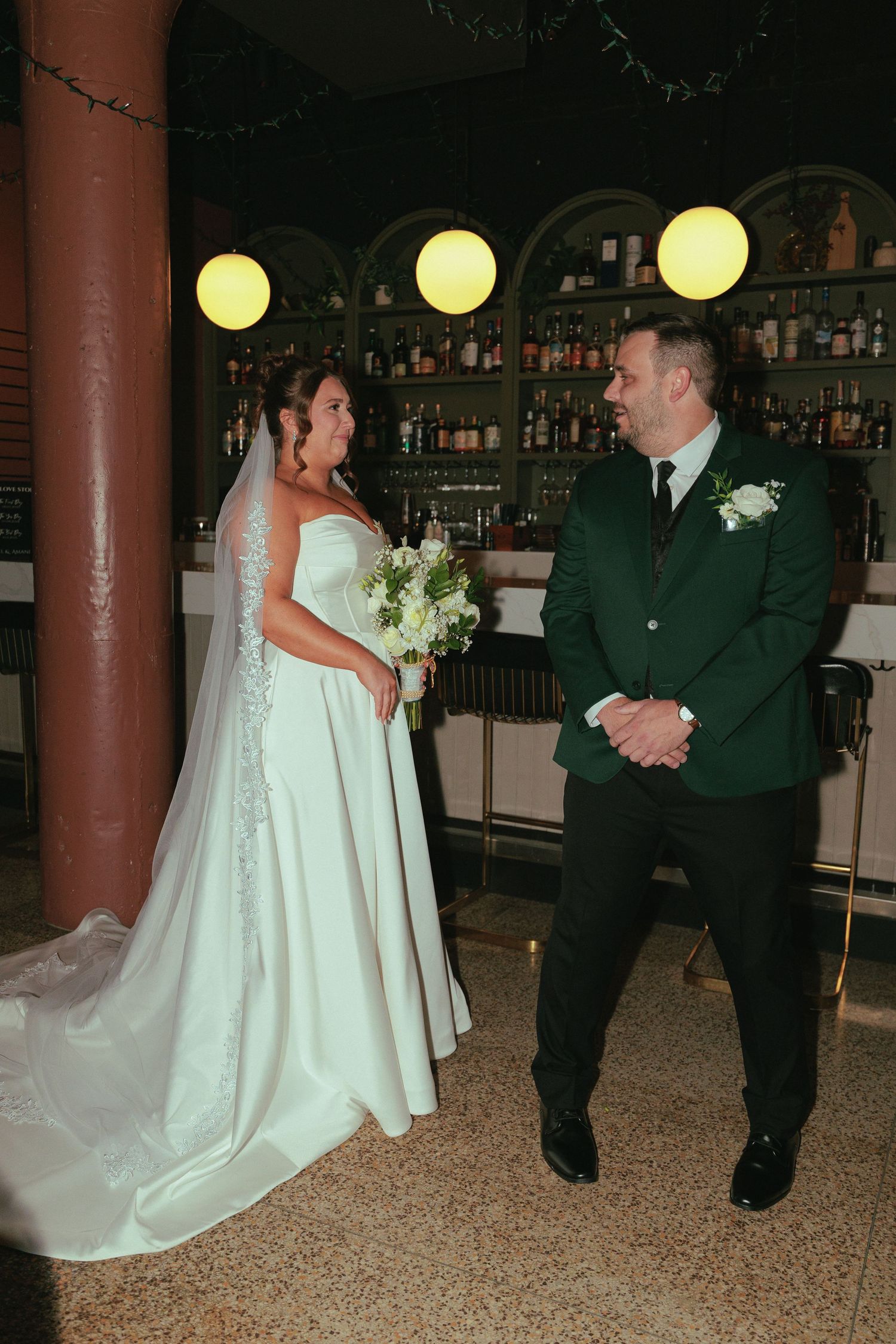 Wedding couple sharing a moment on the dance floor with yellow lighting and bar decor.
