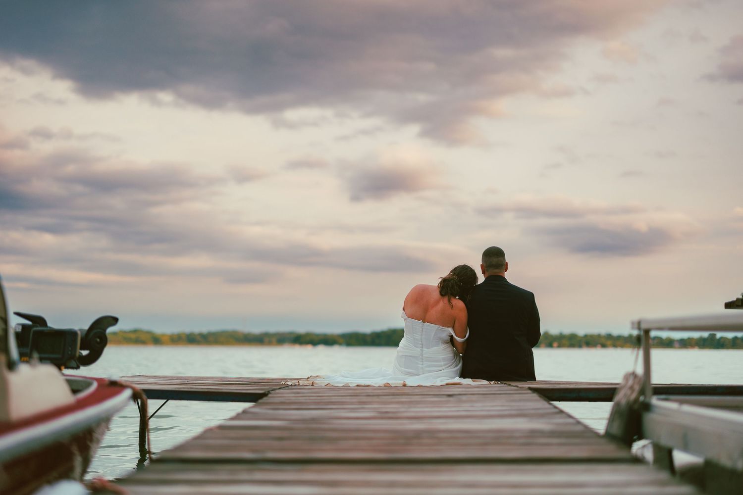 Couple shares a tender moment on a dock at sunset.