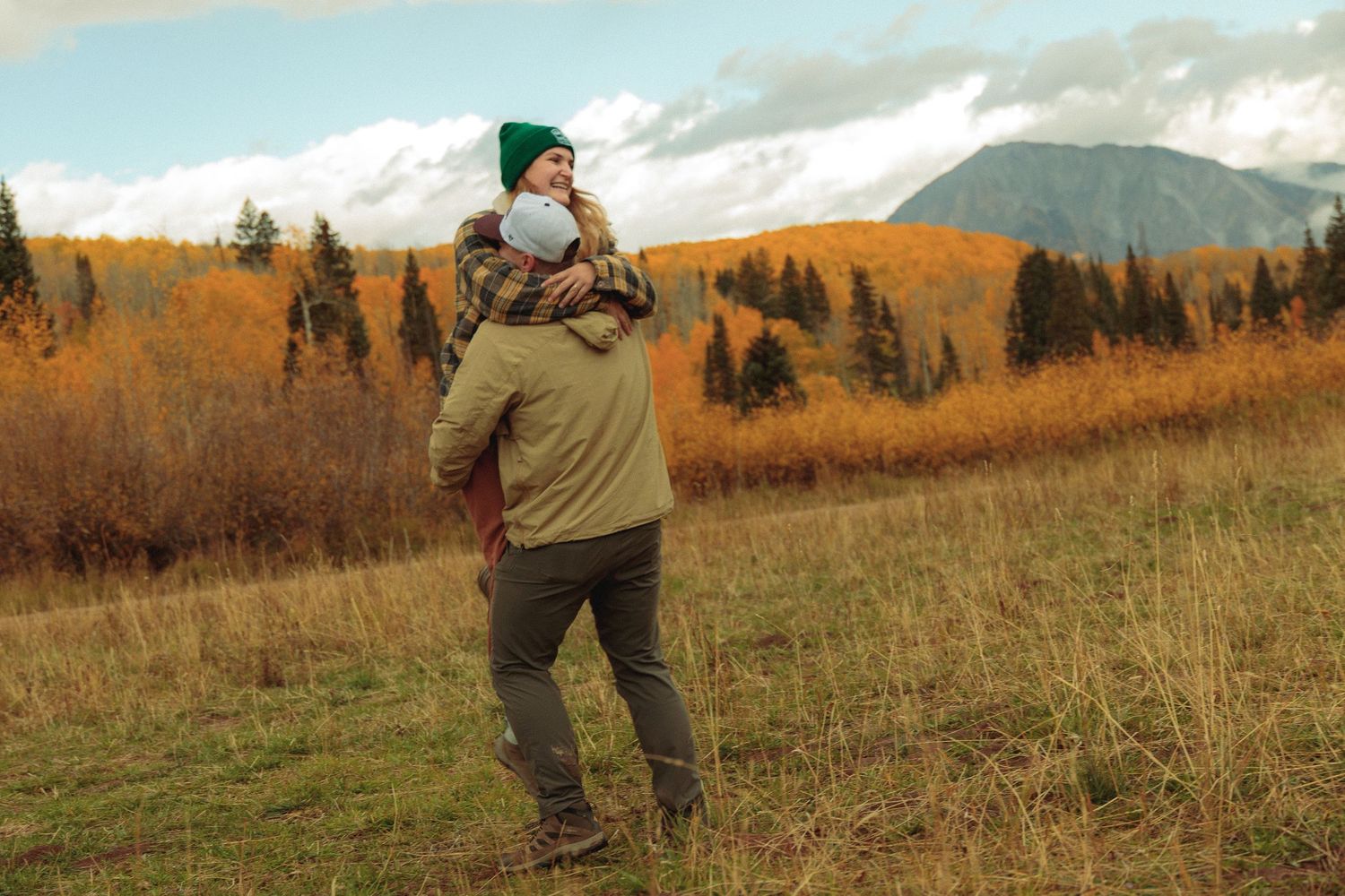 Couple enjoying a moment in a mountain meadow during fall season.