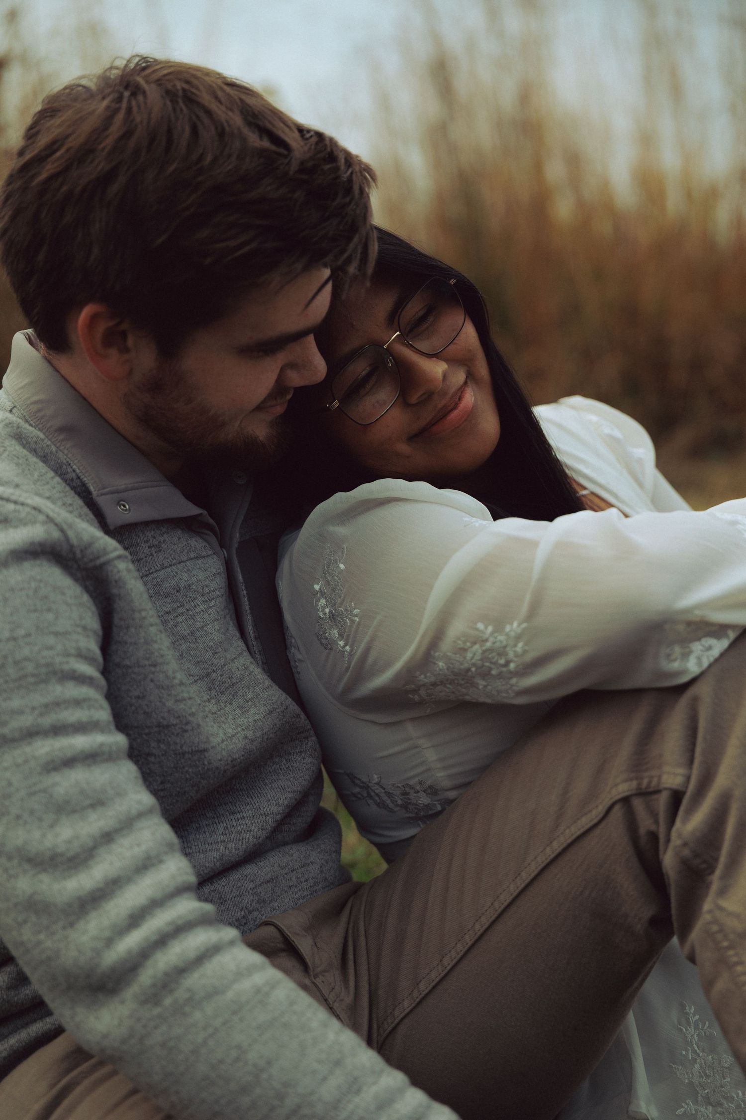 Tender embrace captured in soft natural lighting outdoors.