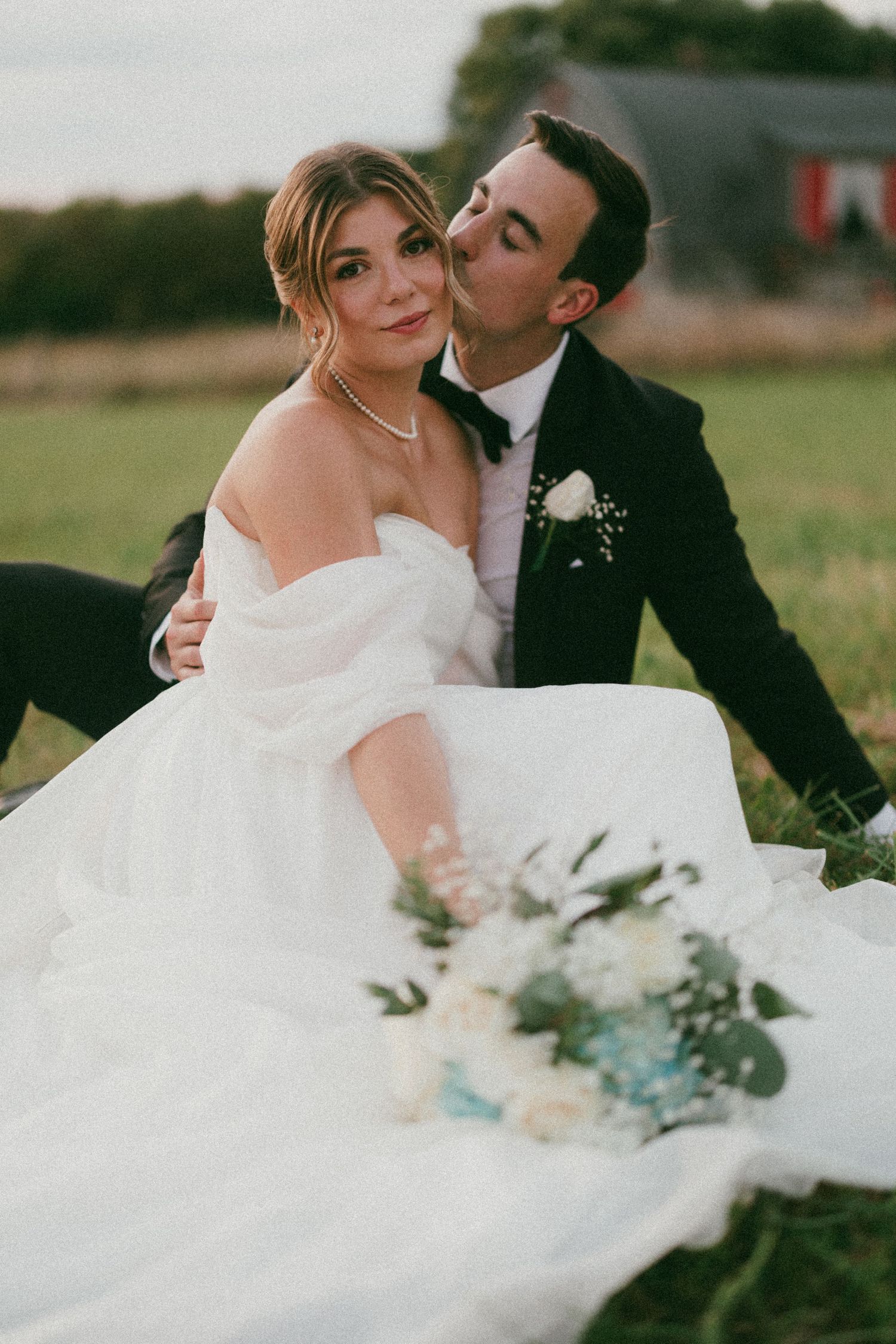 A romantic wedding portrait featuring a flowing white dress against a natural outdoor setting.