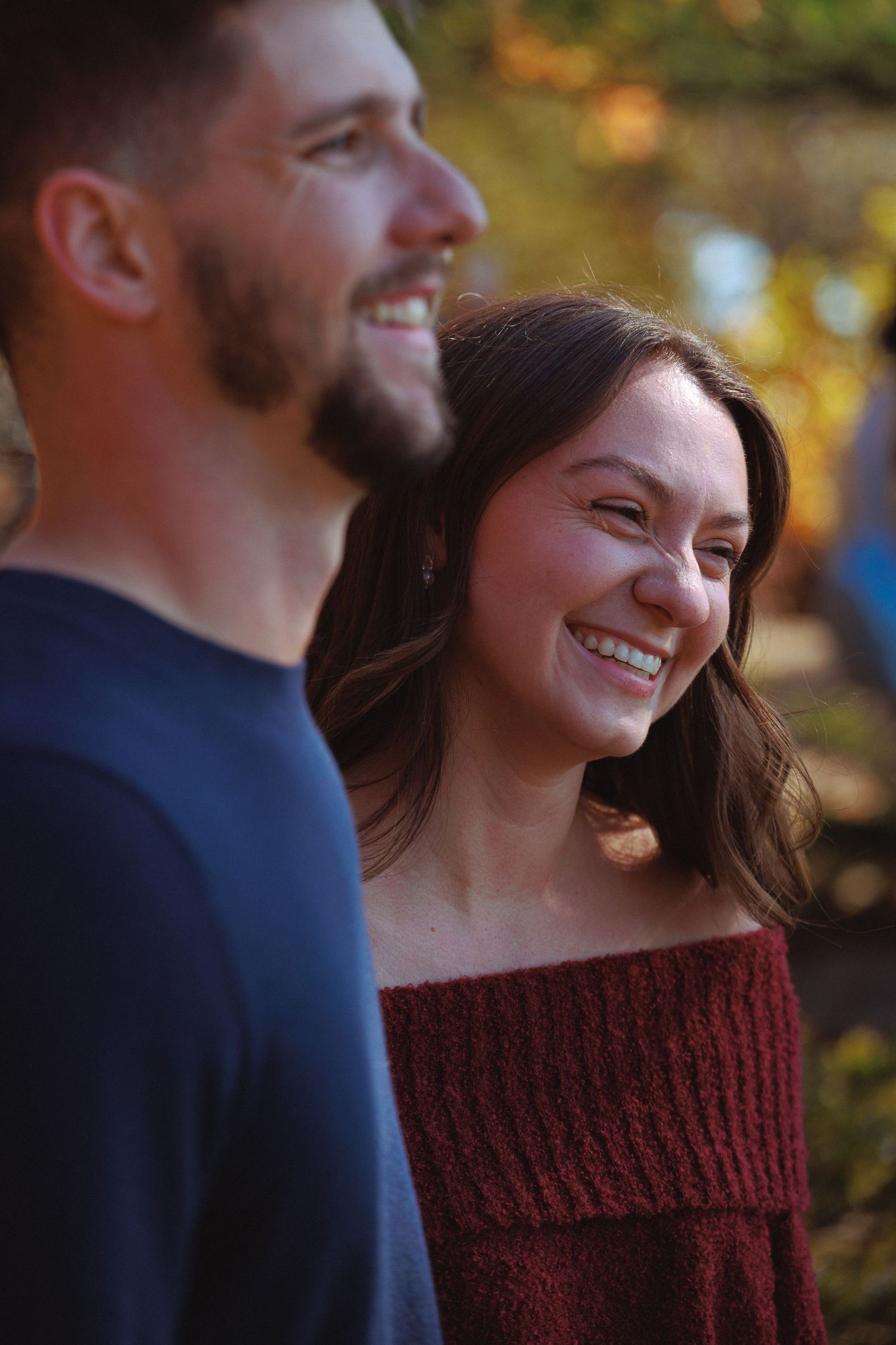 A happy couple smiling together during an autumn photoshoot.