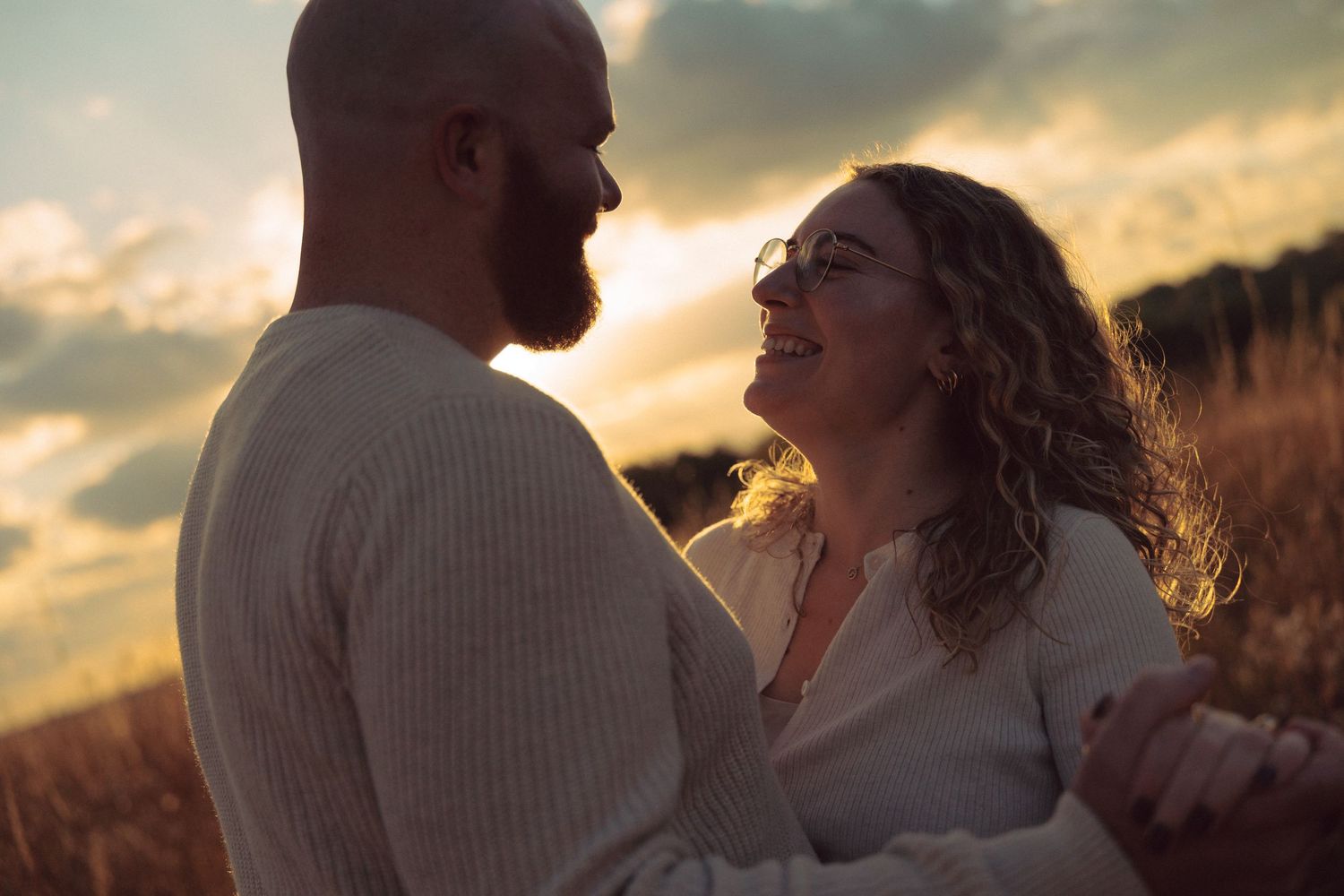 A romantic sunset moment between two people in a field with golden light.