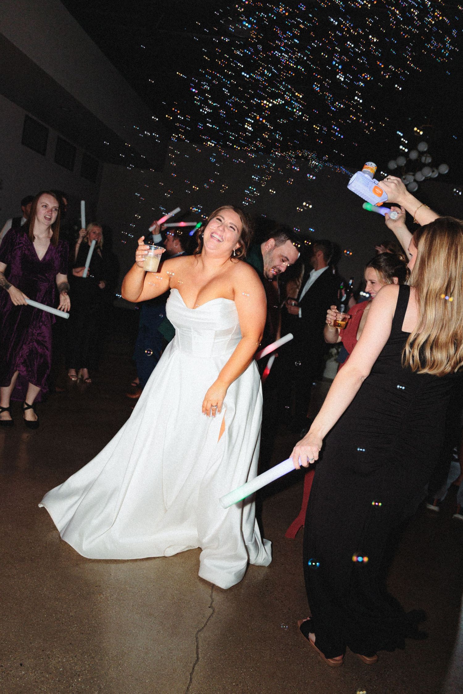 Wedding reception dance party with confetti falling and guests celebrating on the dance floor.