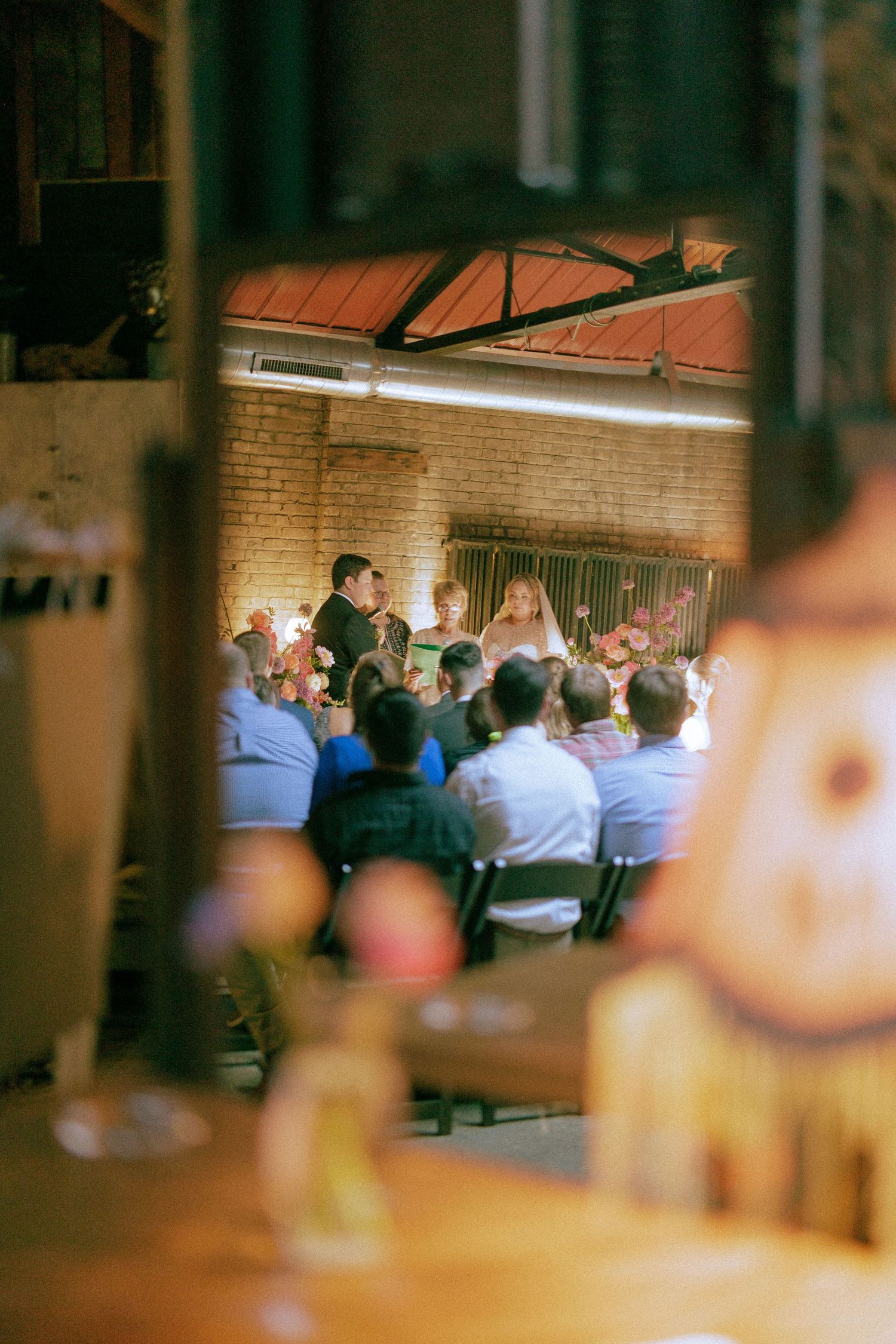 Dimly lit indoor venue with rows of seated guests at tables.