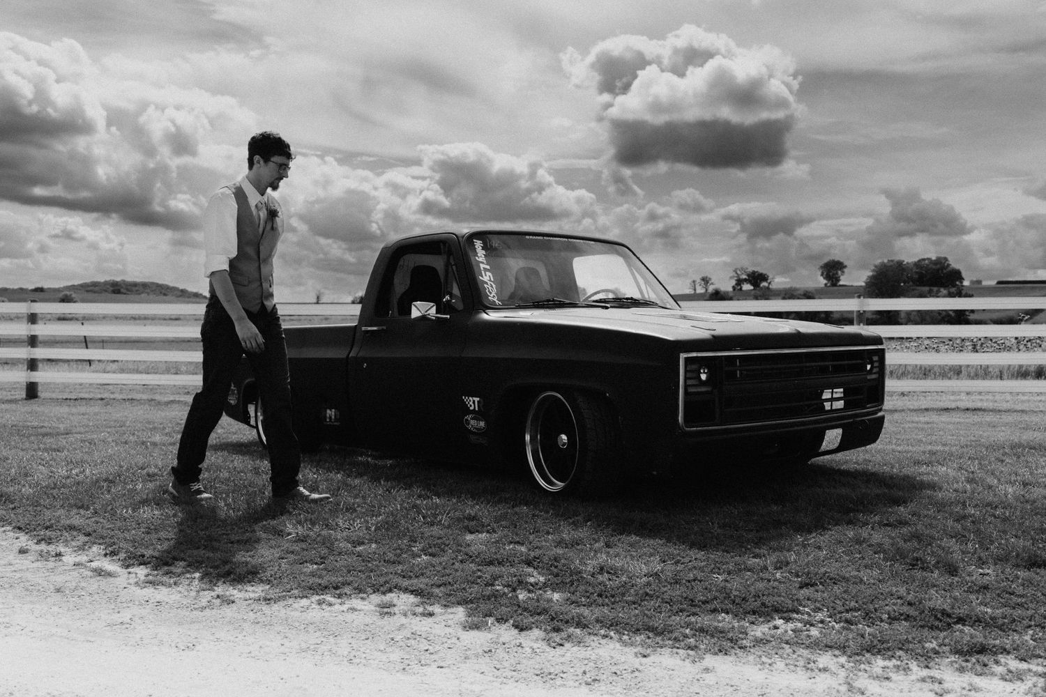 Vintage cars parked on a grassy field against a cloudy sky.