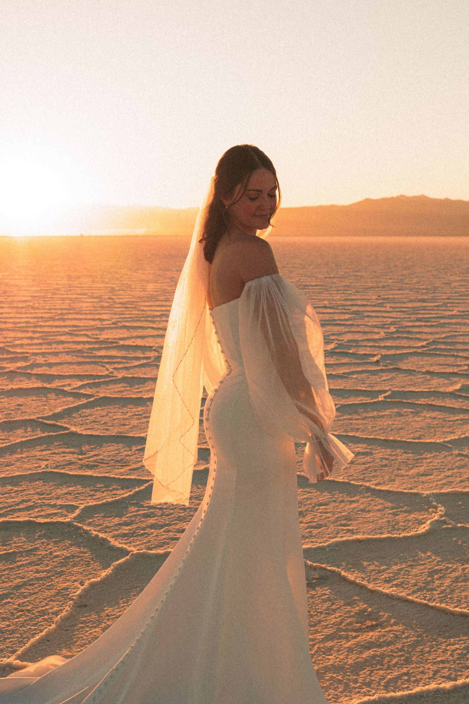 Bride in flowing white dress twirls on utah salt flats during golden hour.