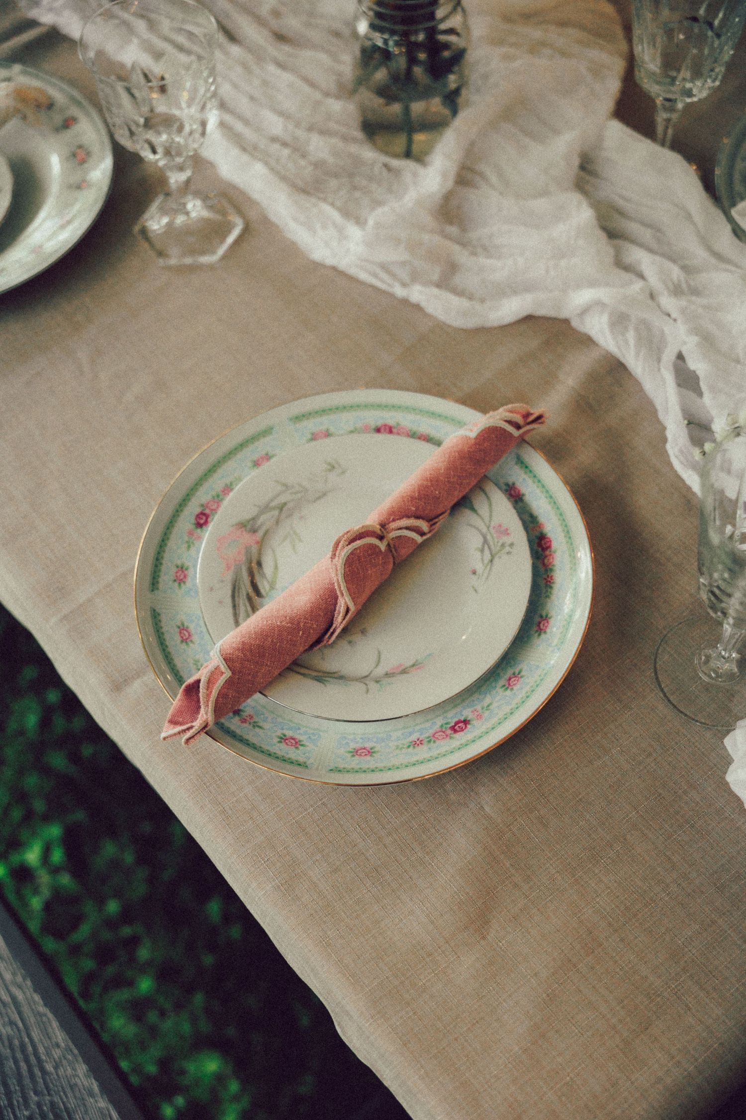 Elegant place setting with vintage china plates and linen tablecloth.