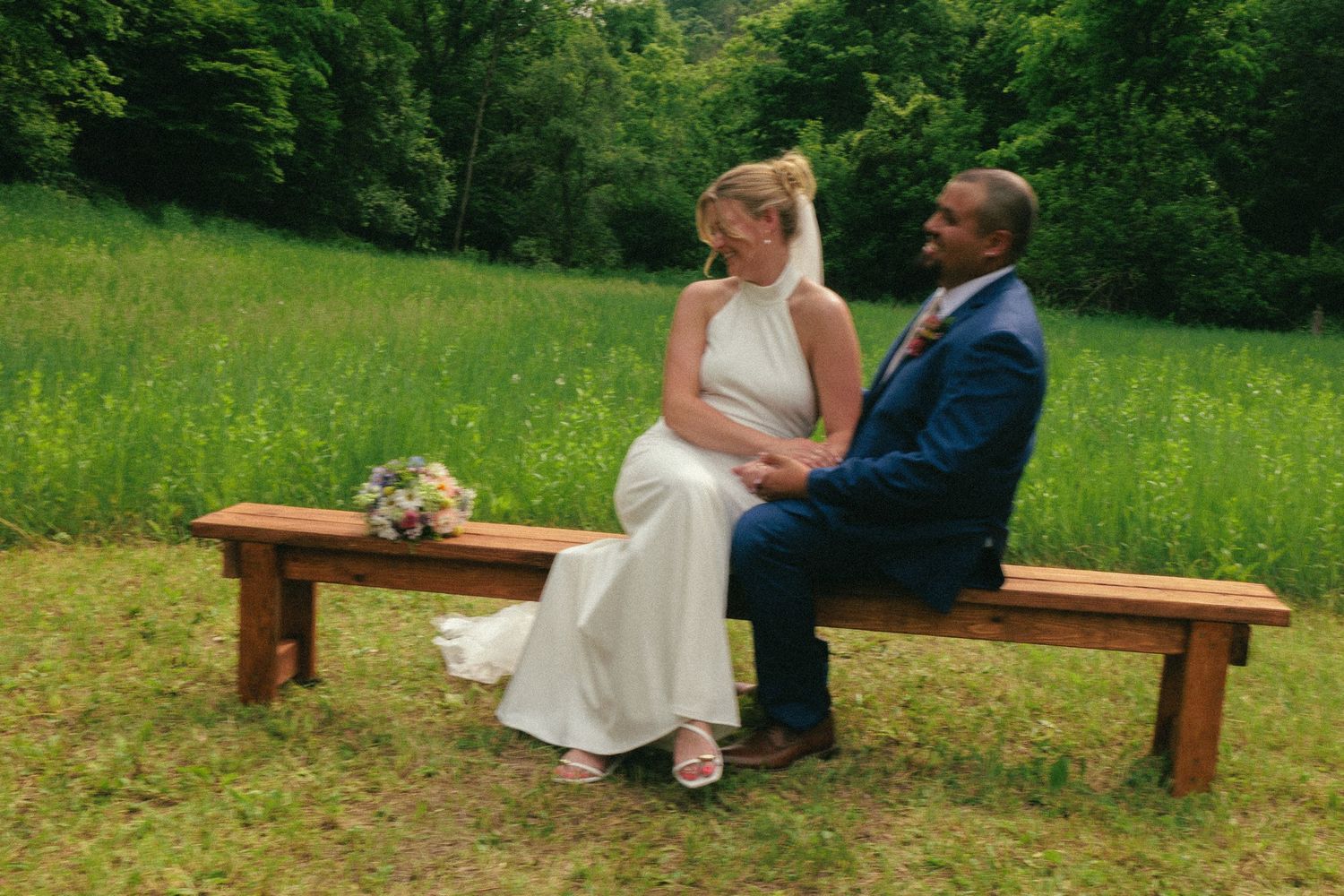 Wooden benches arranged outdoors for a rustic wedding ceremony in a green field.