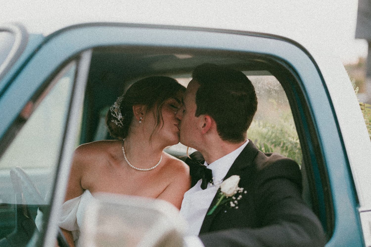 A romantic moment captured inside a vintage car on a wedding day.