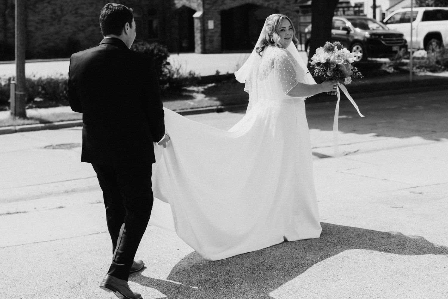 Black and white photo of couple walking together on wedding day.