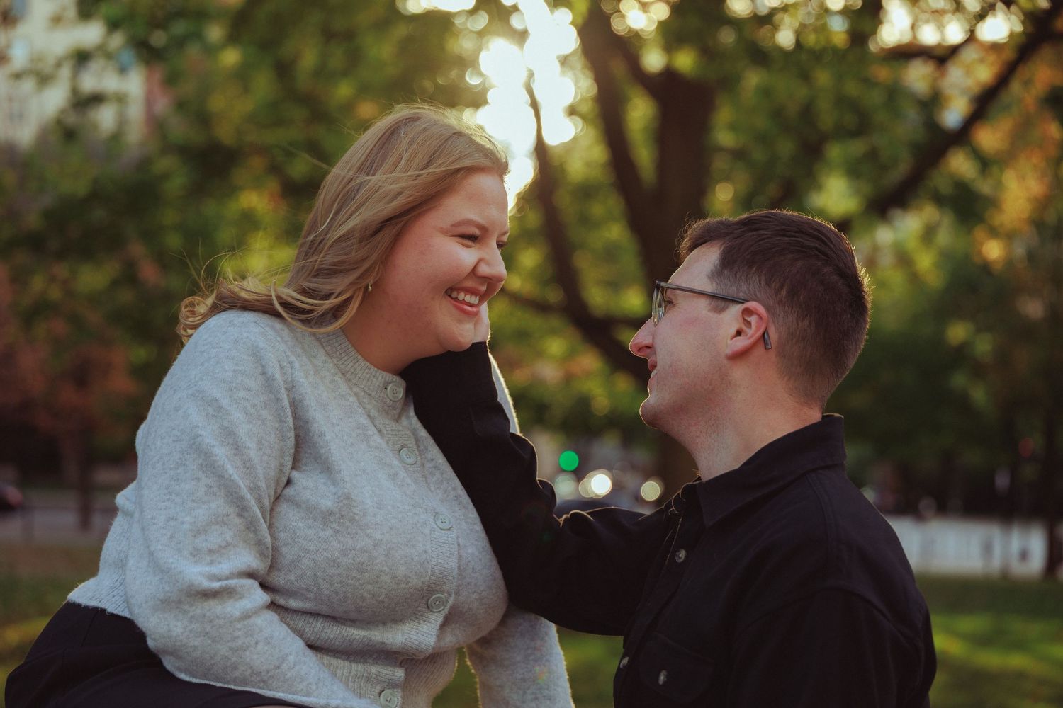 A couple shares an intimate moment together in a sunlit outdoor setting.