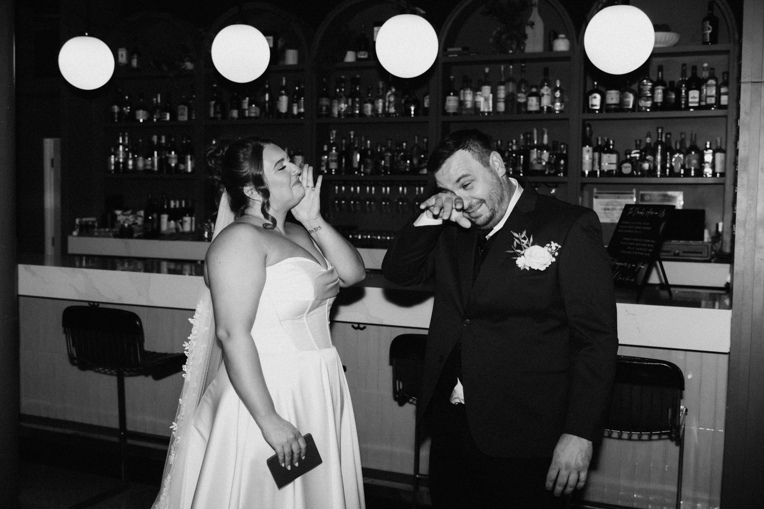 Wedding celebration in a dimly lit bar area with round pendant lights.