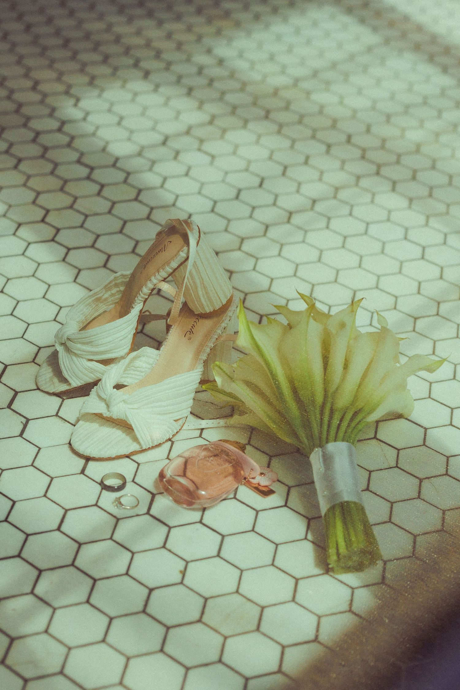 White high heeled bridal shoes arranged artistically on hexagonal tile floor.