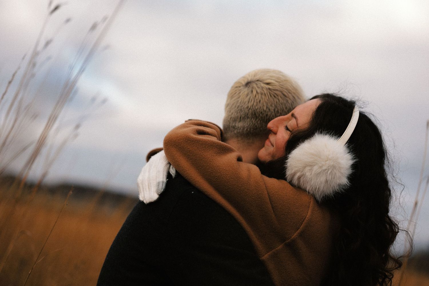 Intimate close-up shot of a couple against a soft cloudy sky background.