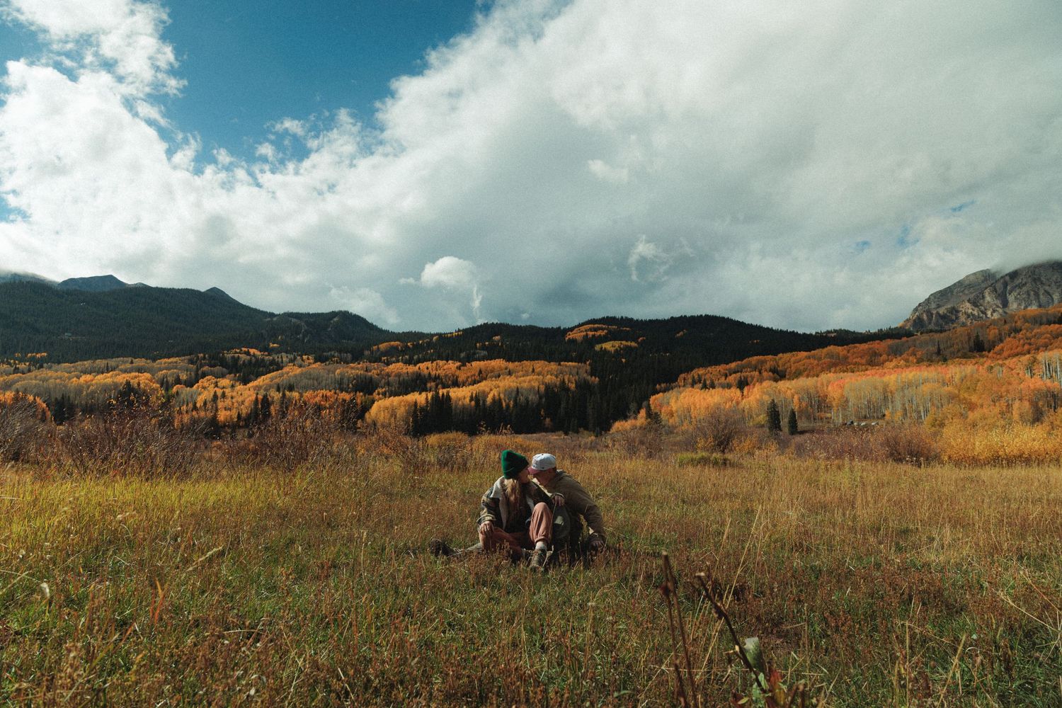 Wide mountain landscape with blue sky and scattered clouds over autumn terrain.