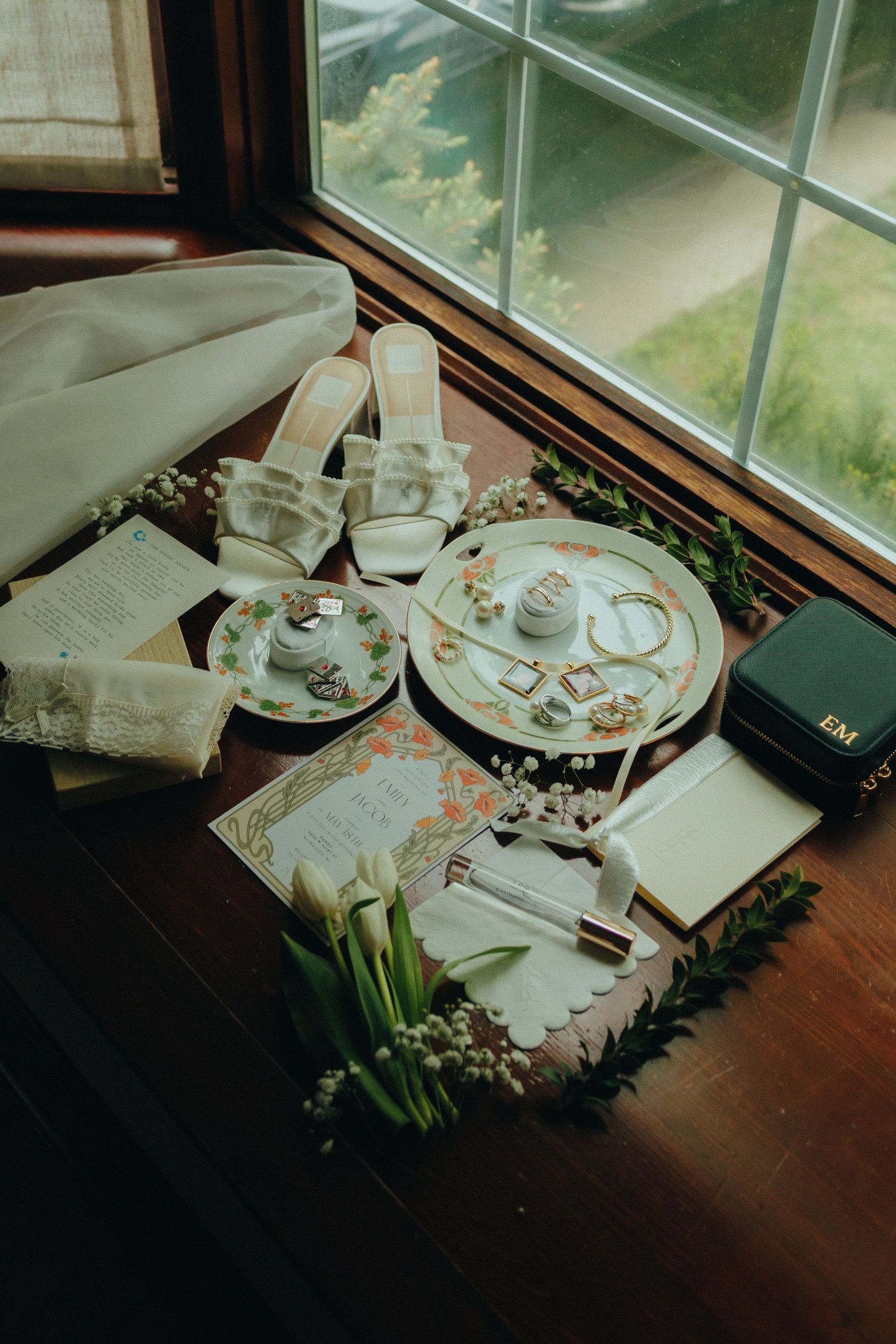 Elegant place settings with white dishes and floral arrangements on a wooden table by a window.