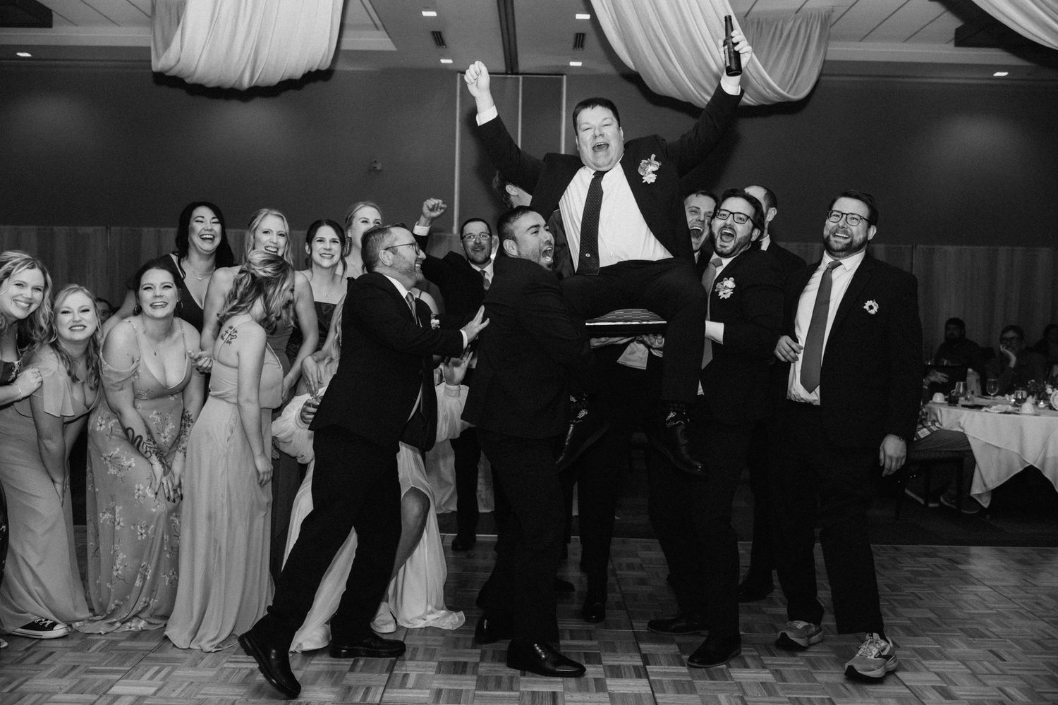 Black and white photo of wedding guests dancing and celebrating on the dance floor.