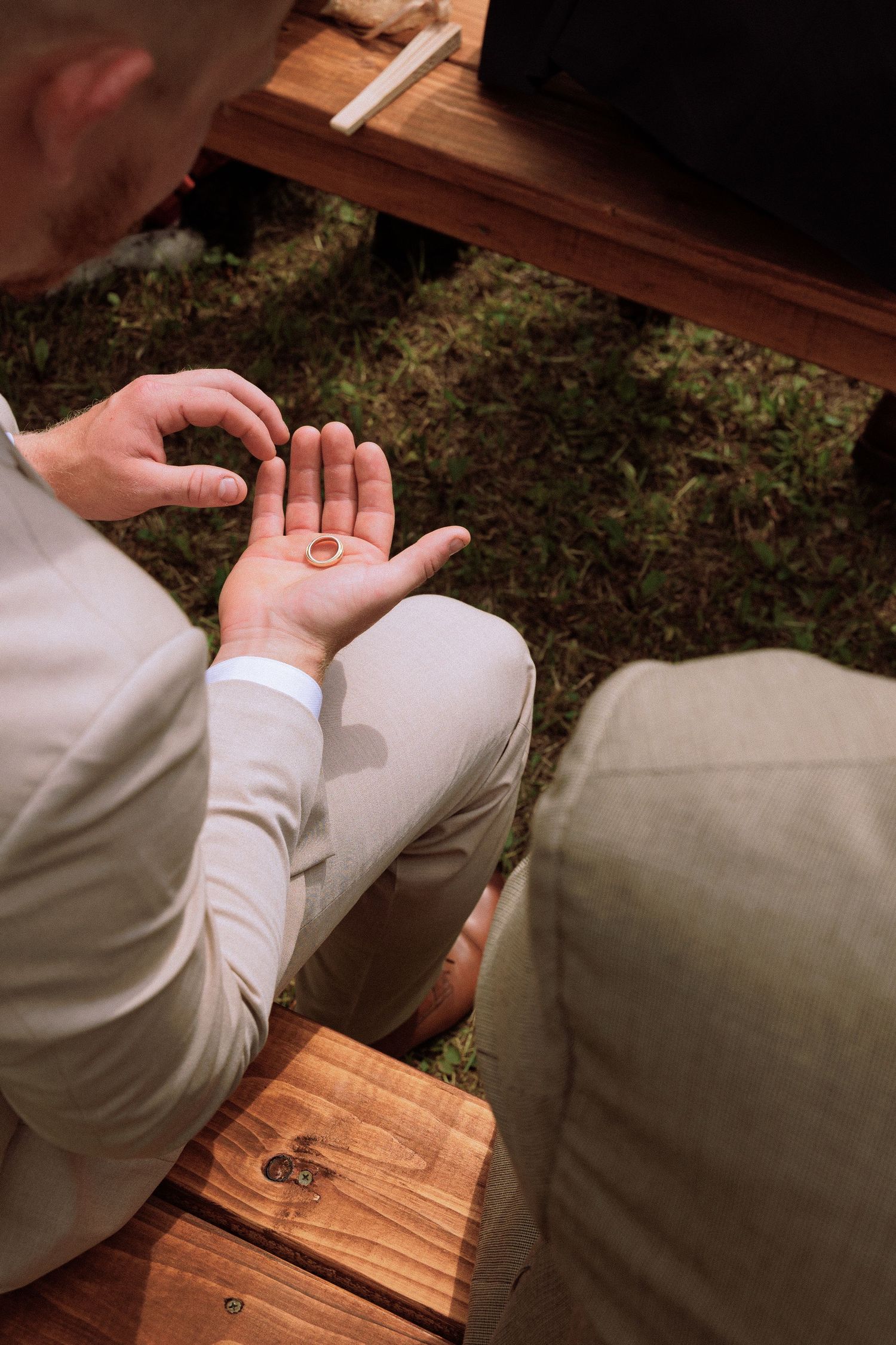 Close-up shot of wedding rings resting on a wooden surface during an outdoor ceremony.