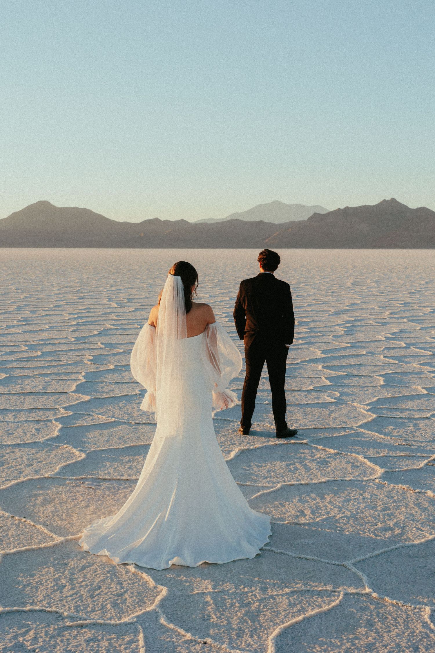 Wedding couple poses on the stark white Bonneville Salt Flats during sunset.