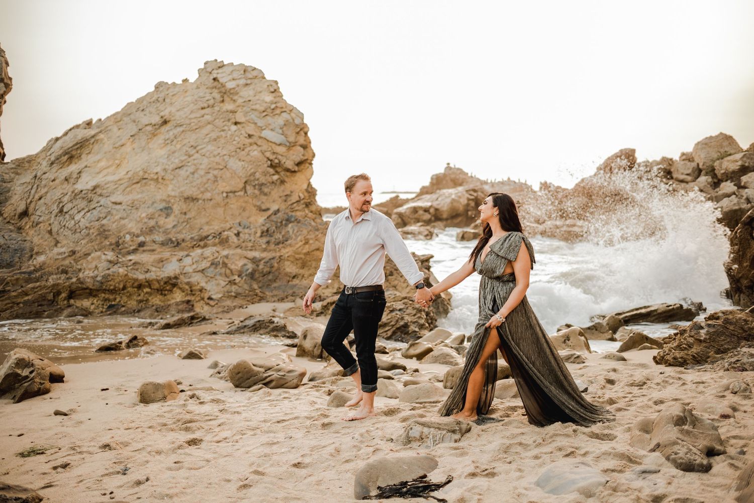 Romantic photoshoot on rocky beach landscape during golden hour.