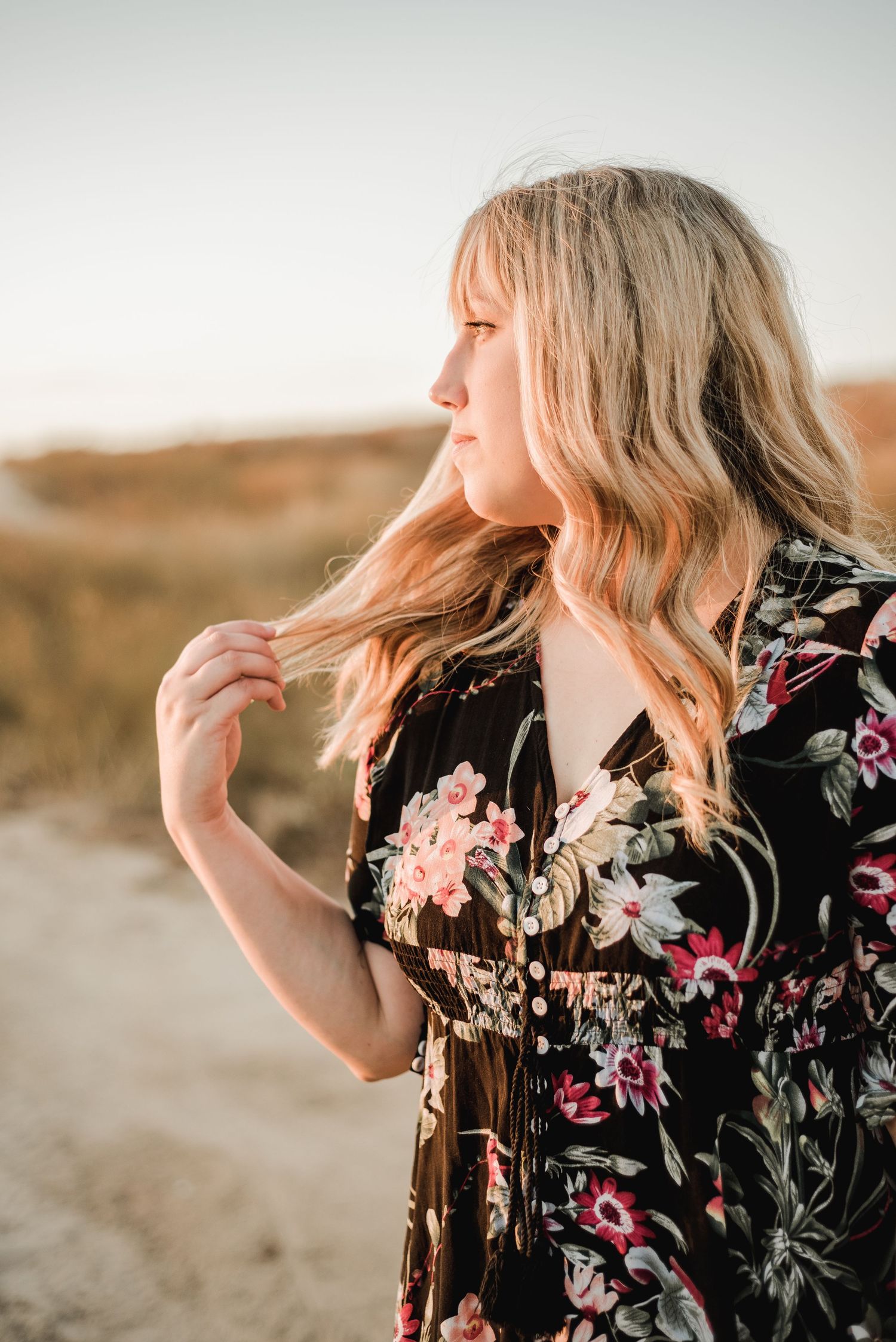 A profile view captures flowing hair and floral dress details in warm sunset lighting.