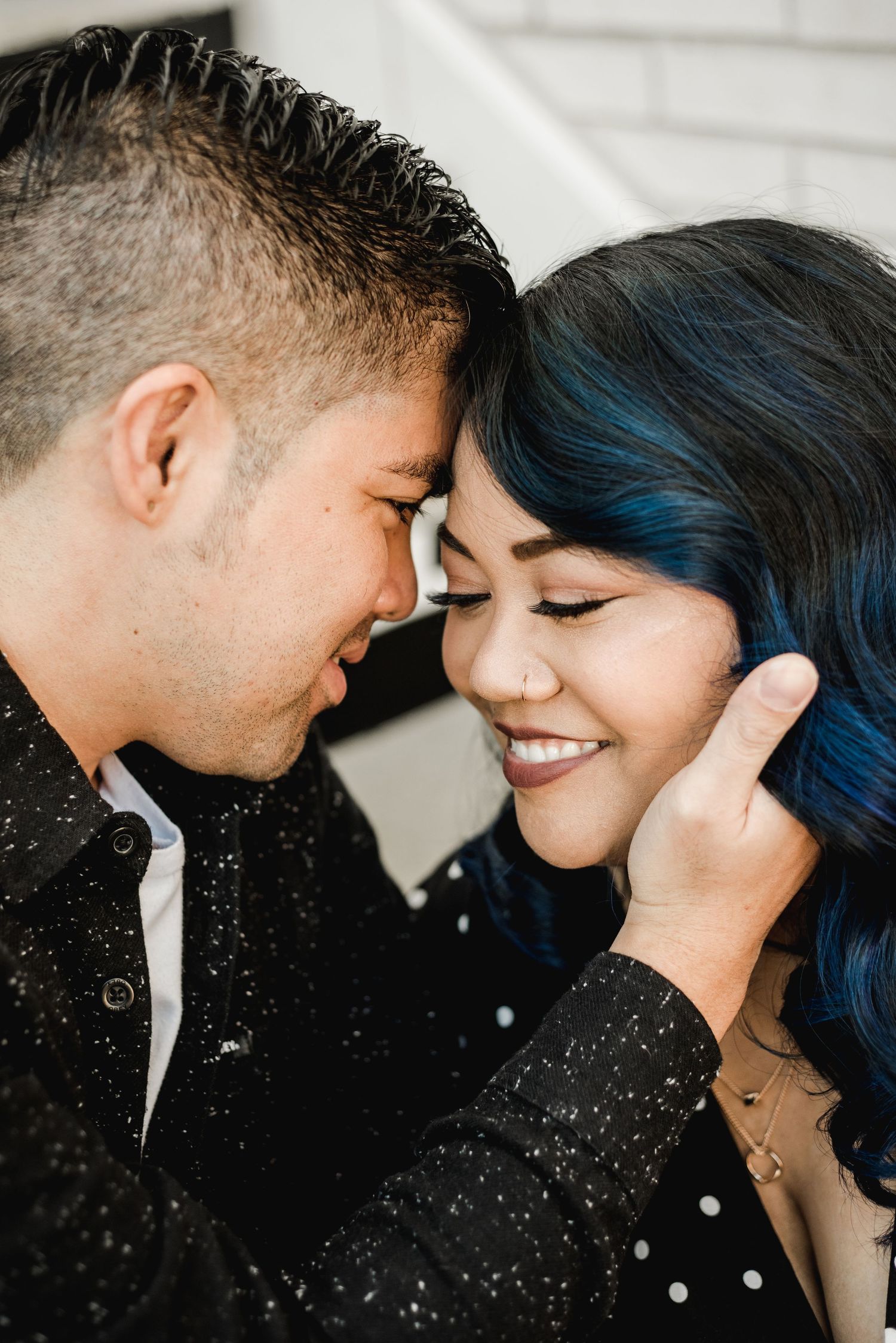 Intimate close-up portrait of couple sharing tender moment against white background.