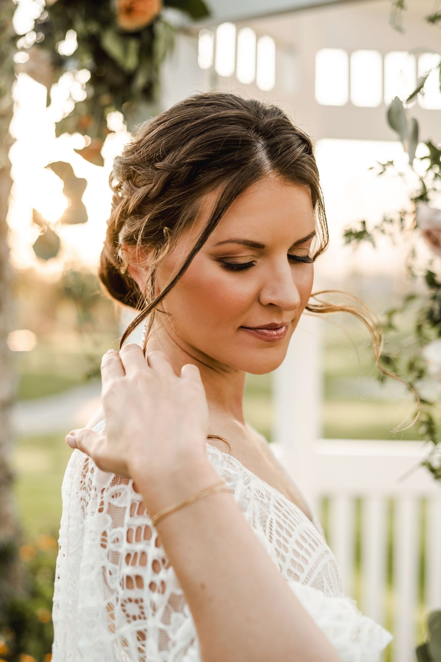 Bride in lace dress with elegant makeup and updo hairstyle at sunset.