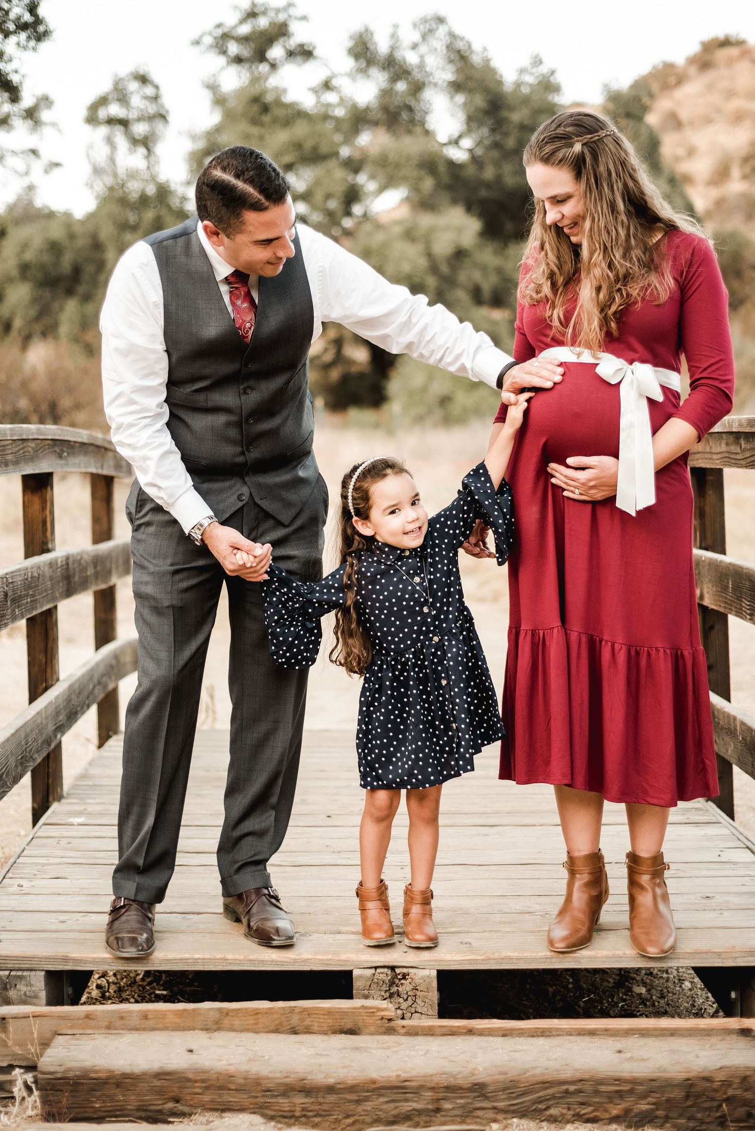 A family shares playful moments on a wooden boardwalk during an outdoor photoshoot.