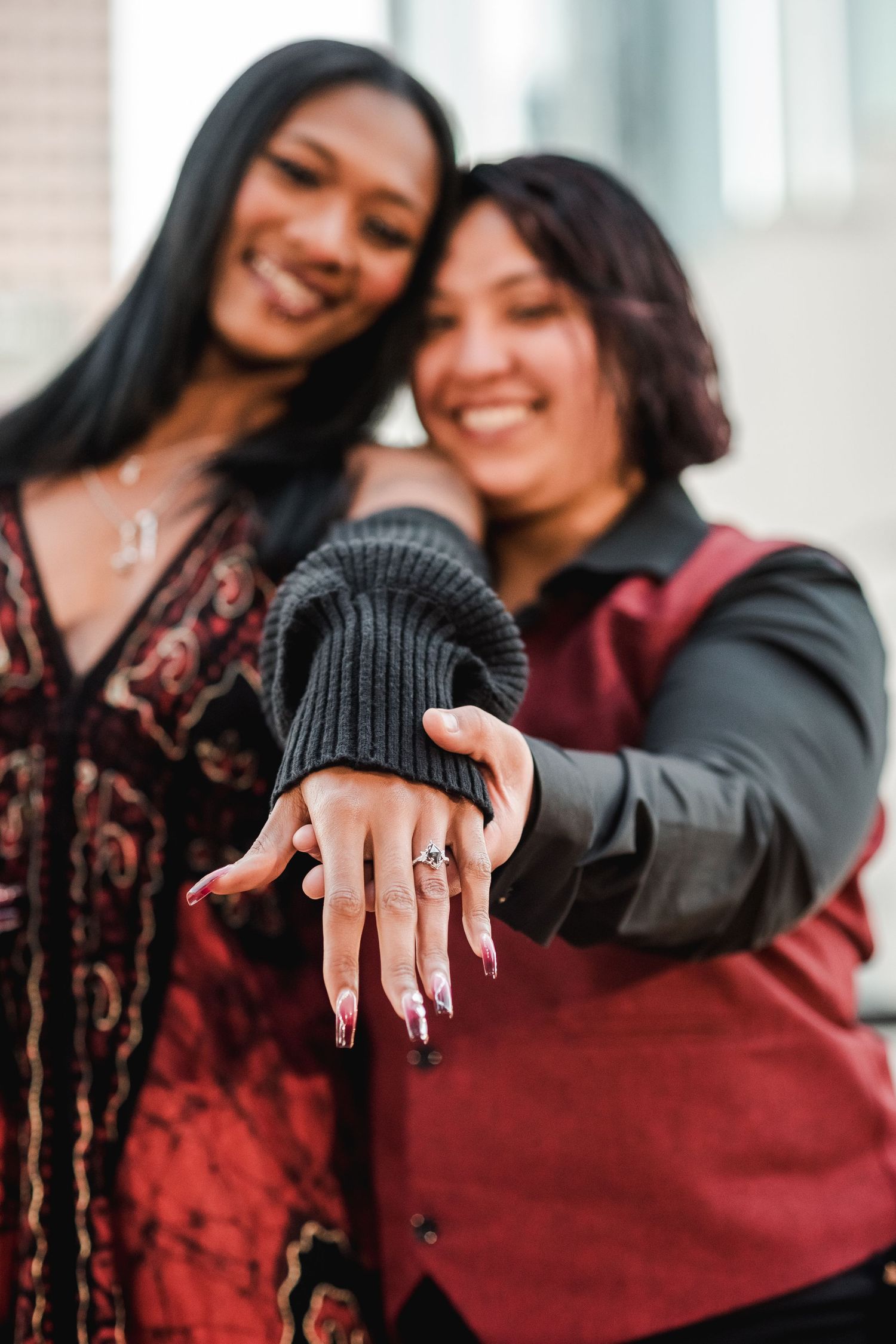 Happy couple showing off engagement ring with joyful expressions.