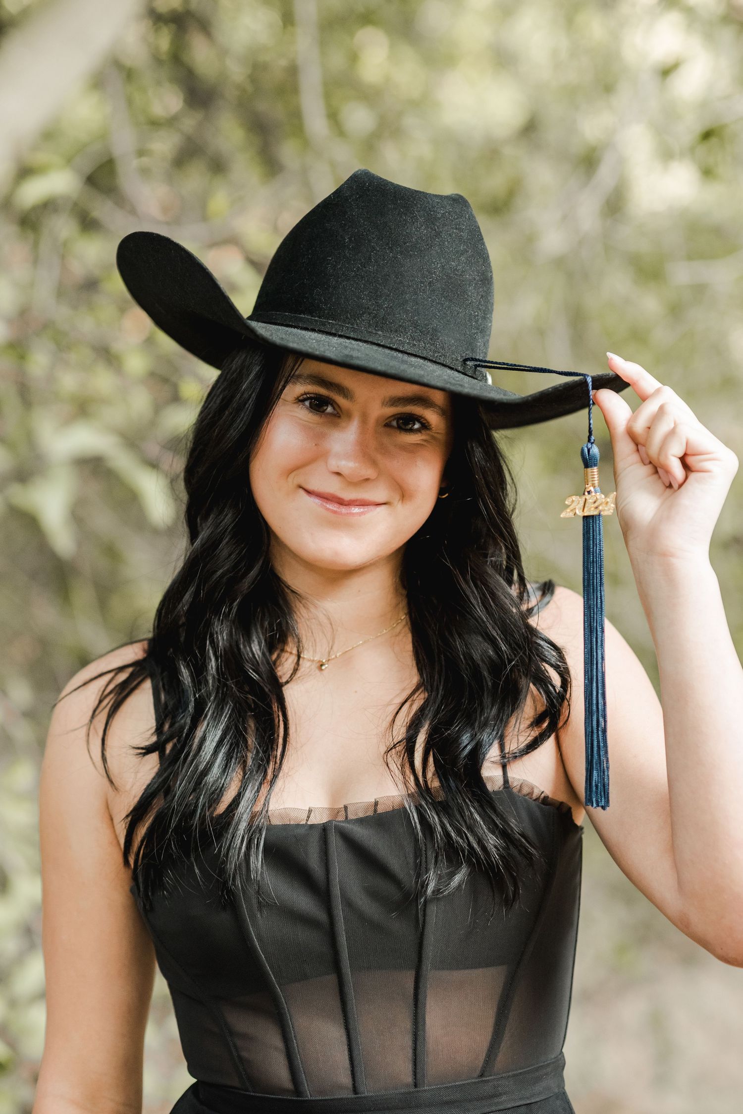 Graduation photos featuring a black hat with tassel against a natural outdoor background.