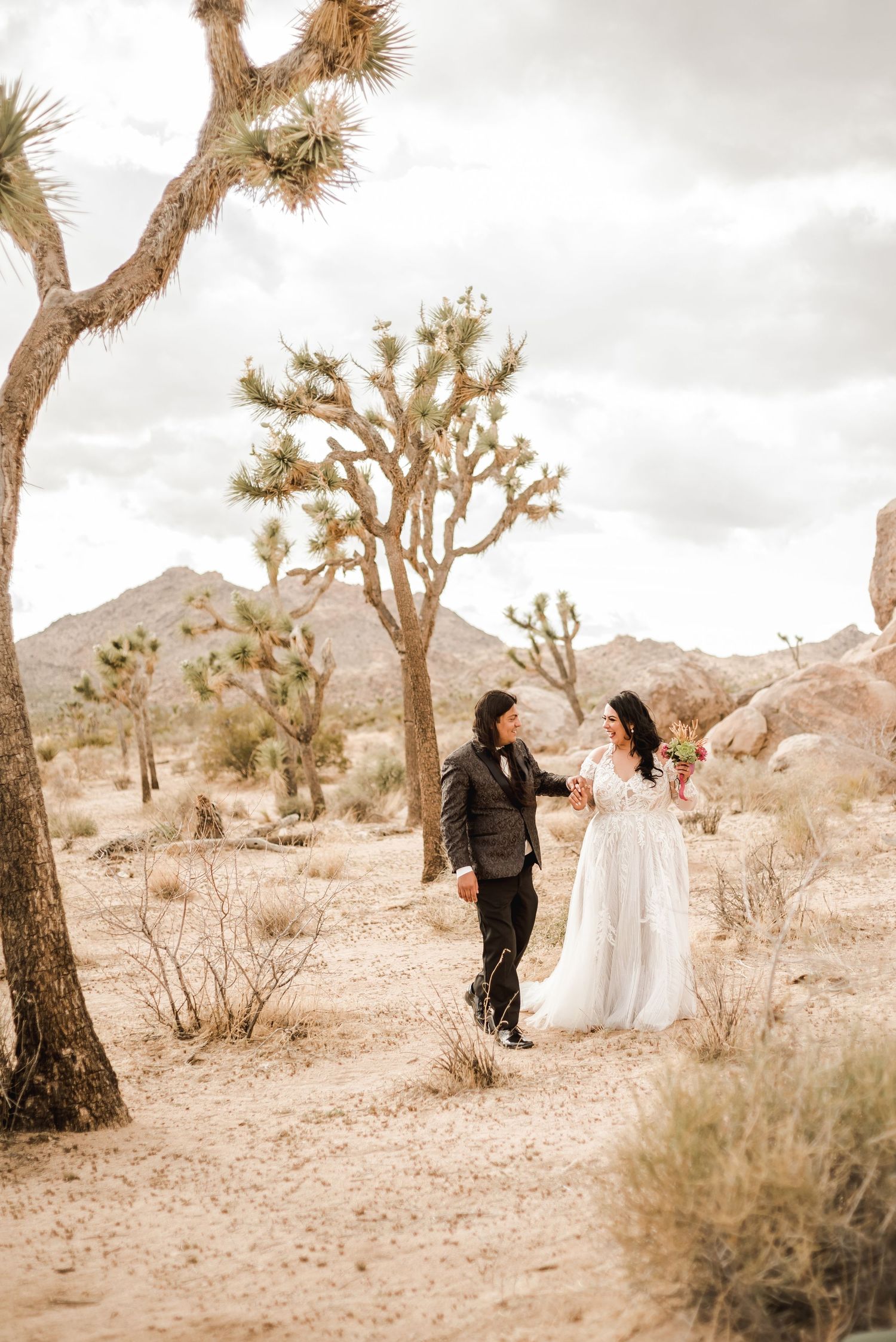 Desert wedding photoshoot with Joshua trees creating a dramatic backdrop in golden light.