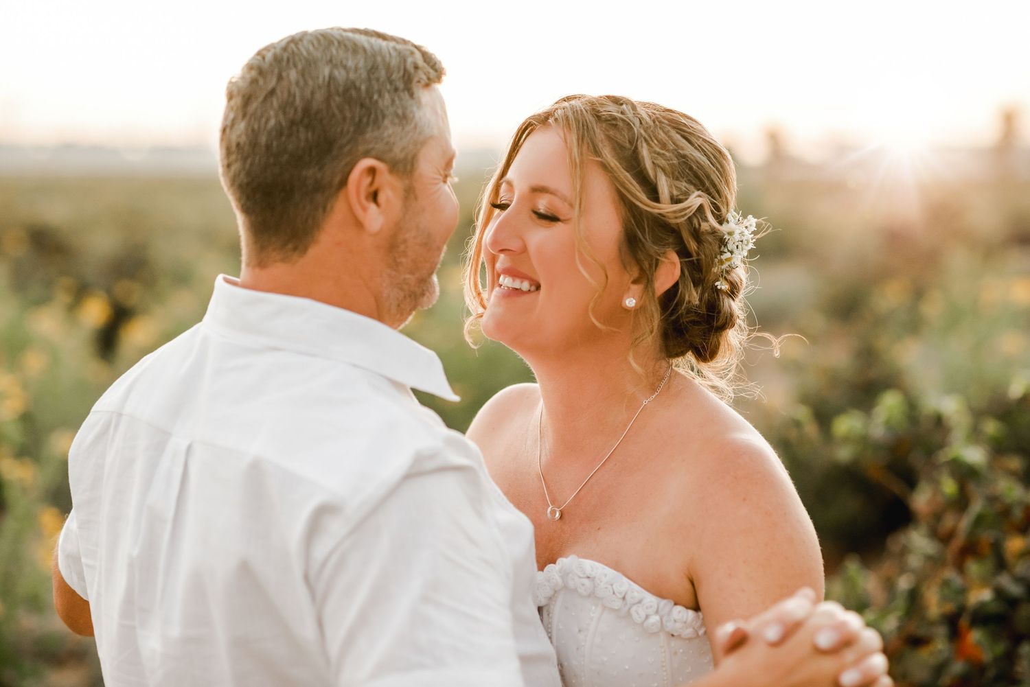 An intimate wedding portrait captured during golden hour in a rustic outdoor setting.