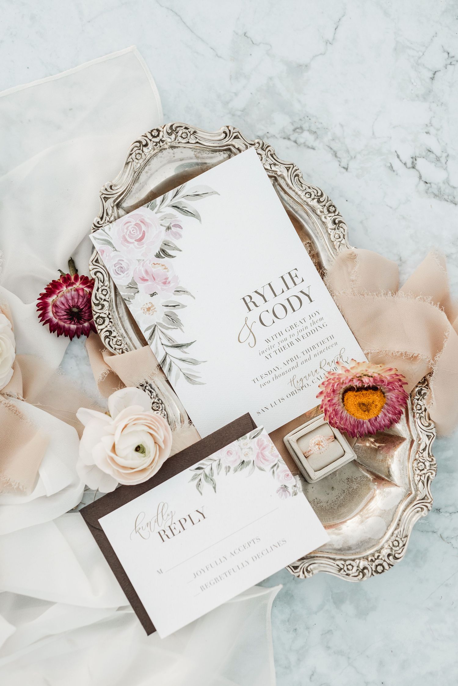 Wedding invitation suite with floral details and ornate silver tray styling.